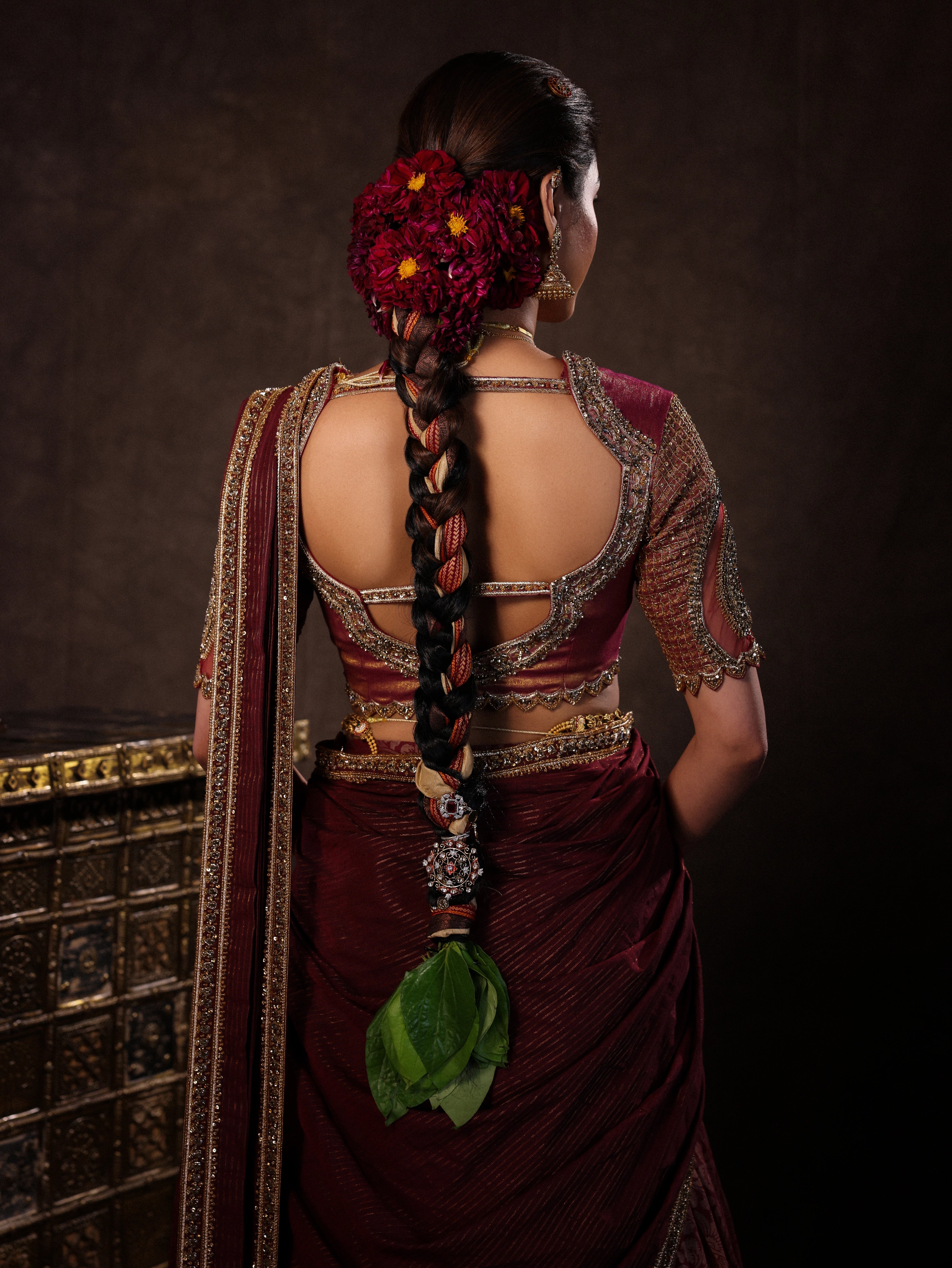 Model Dr Sree Advaita showcasing back blouse design in a brownish maroon silk half saree set intricately handcrafted with zardozi, resham, cutdana, sequins & rhinestones. Team Archana Karthick completed the style with maroon glass bangles, a ring, jhumkas, nose ring and a maang tikka.