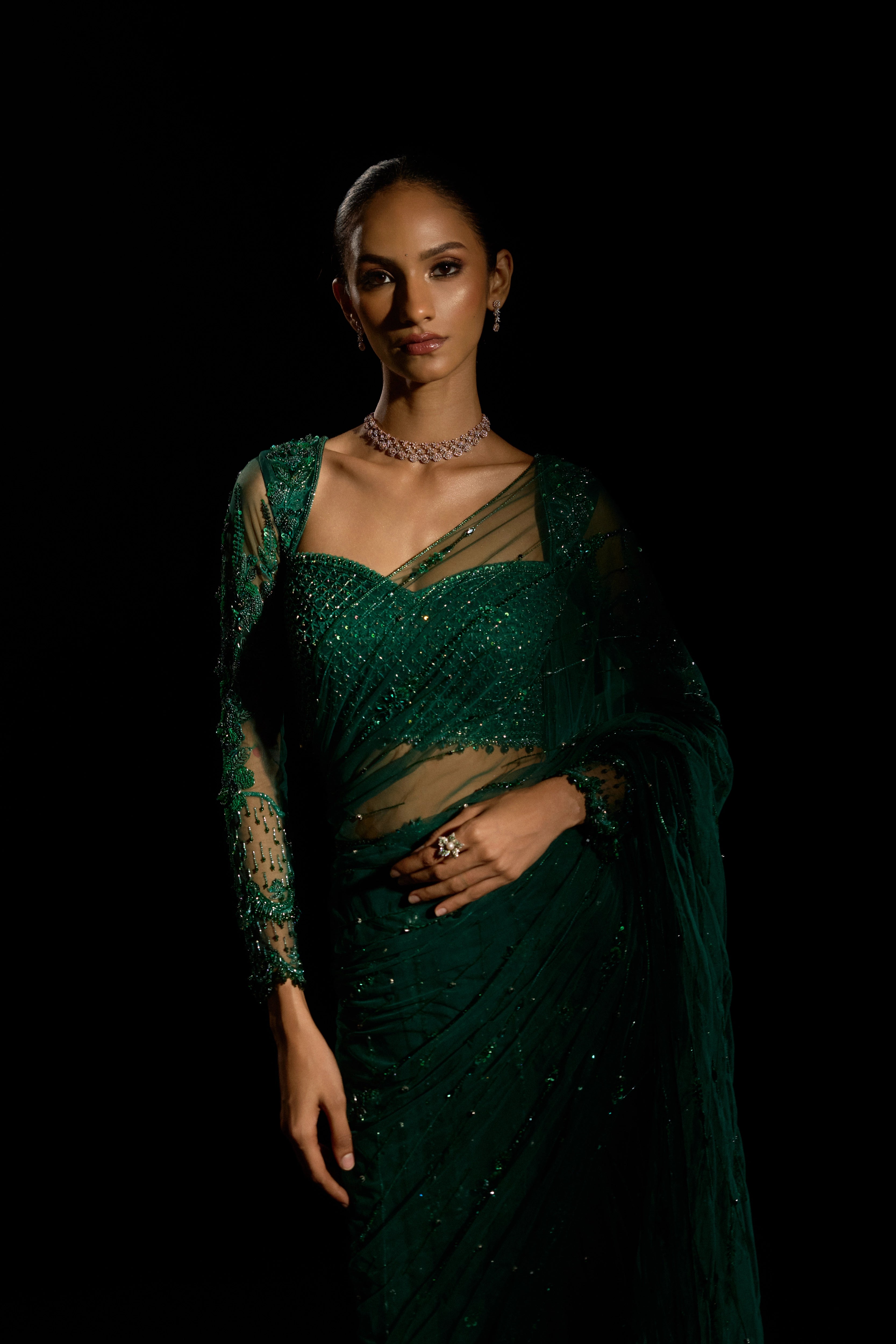 Model Esha Gohil looking straight at the camera for a photoshoot in a bottle green saree set is intricately adorned with sequins, rhinestones, crystals and cutdana for "STARDUST" - A/W'25 saree collection by team Archana Karthick.