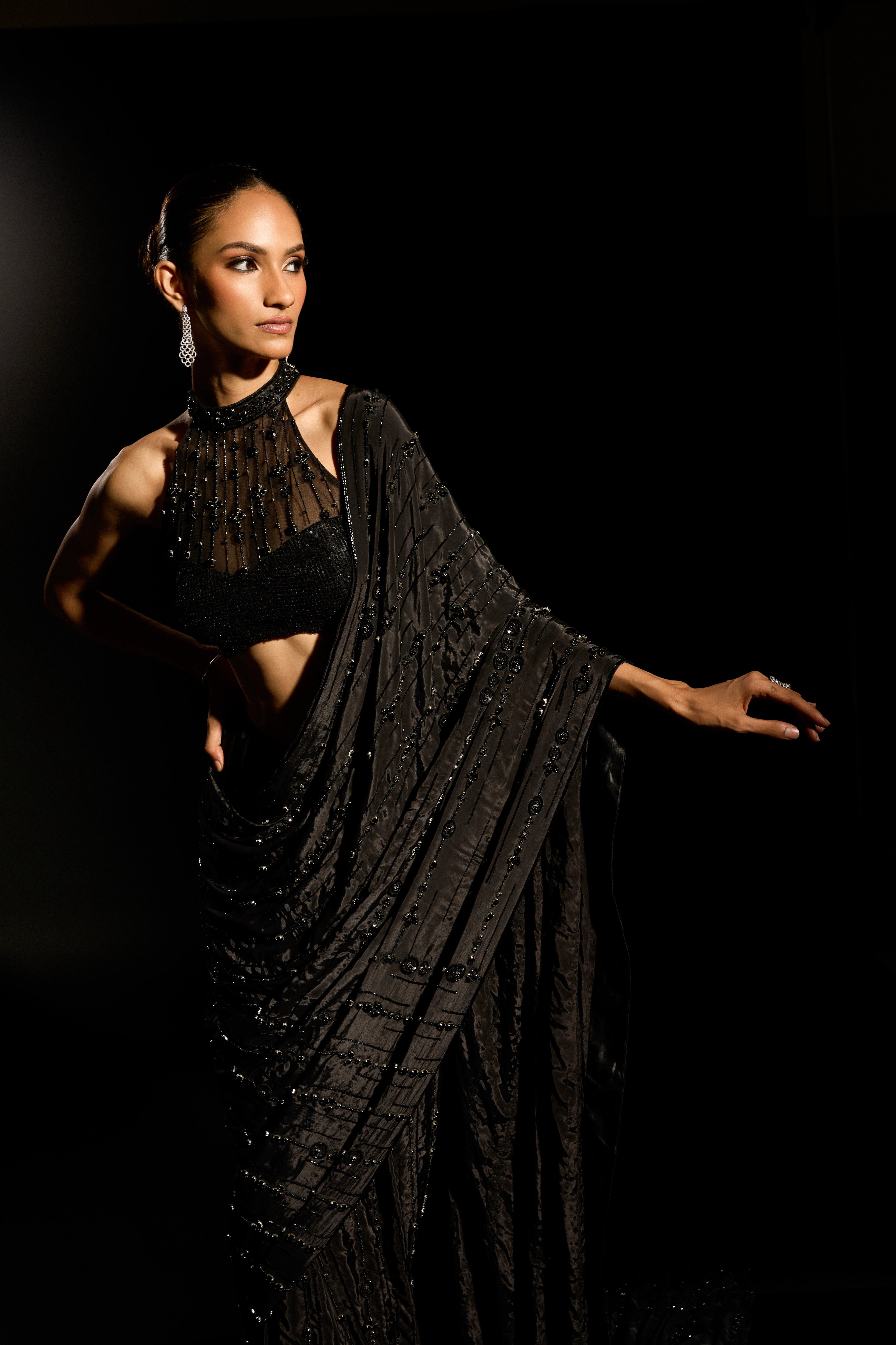 Model Esha Gohil posing during photoshoot in a black saree set is intricately adorned with sequins, rhinestones and cutdana for "STARDUST" - A/W'25 saree collection by team Archana Karthick.