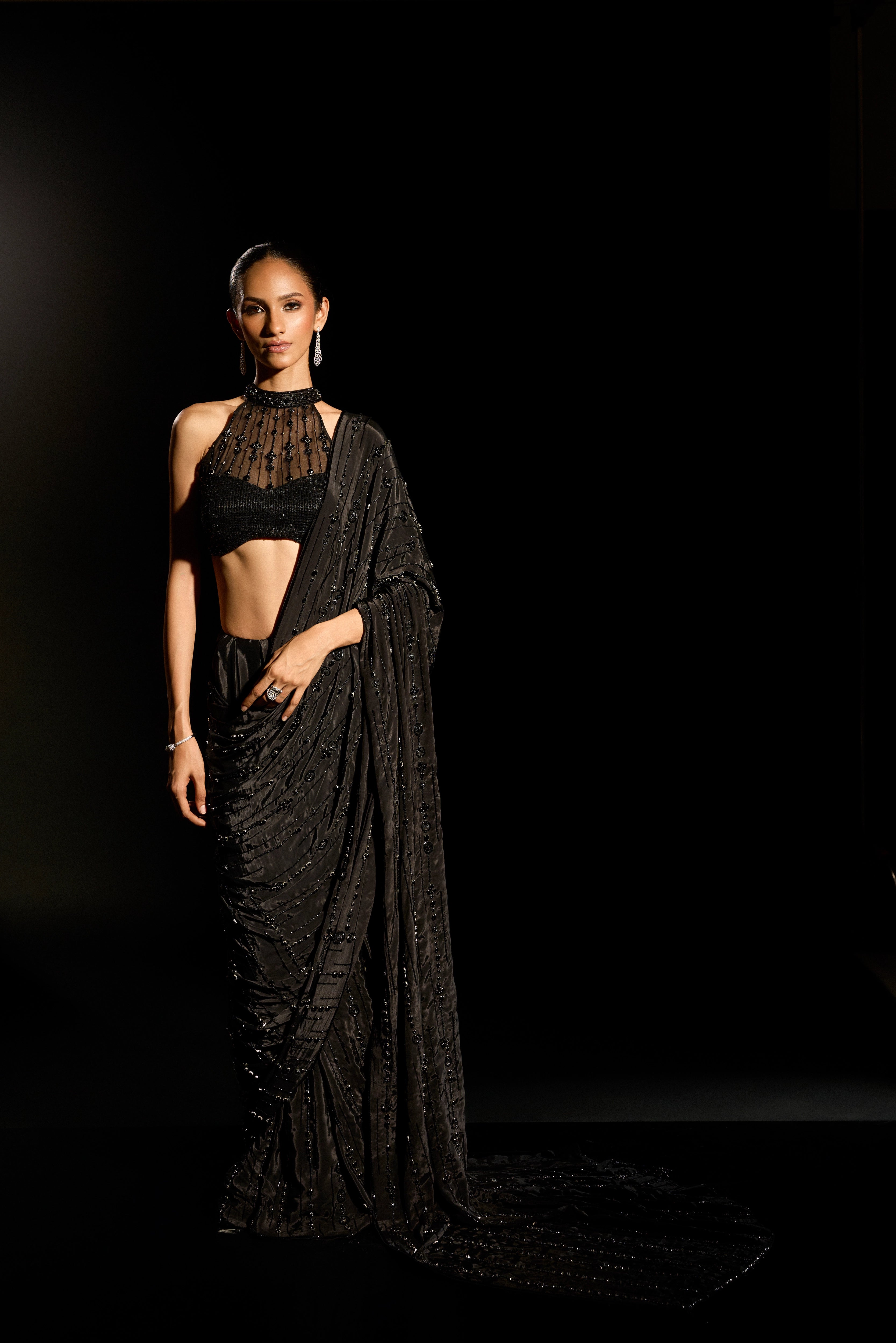 Model Esha Gohil posing in a black saree set is intricately adorned with sequins, rhinestones and cutdana for "STARDUST" - A/W'25 saree collection by team Archana Karthick.