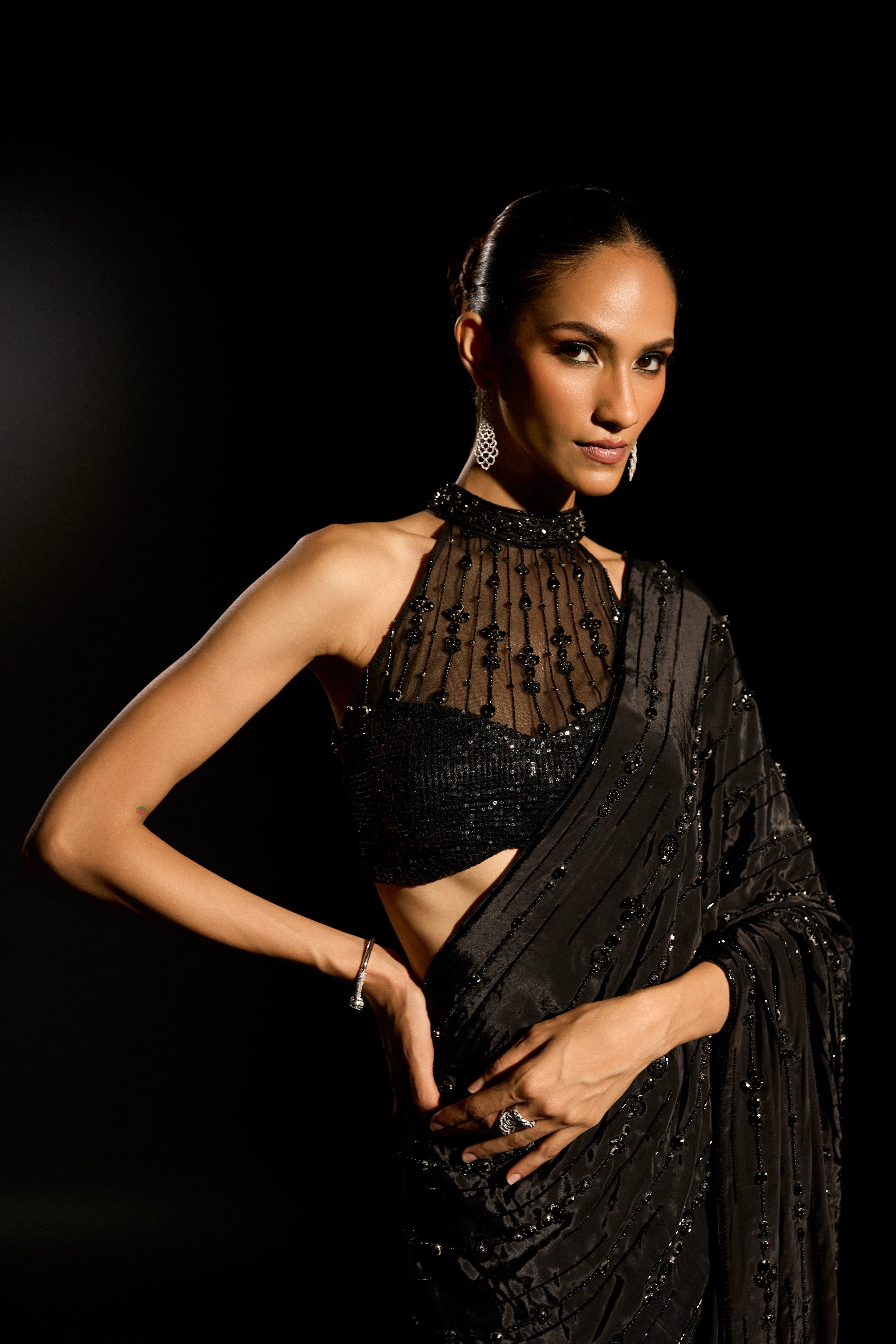 Model Esha Gohil smiling during photoshoot in a black saree set is intricately adorned with sequins, rhinestones and cutdana for "STARDUST" - A/W'25 saree collection by team Archana Karthick.