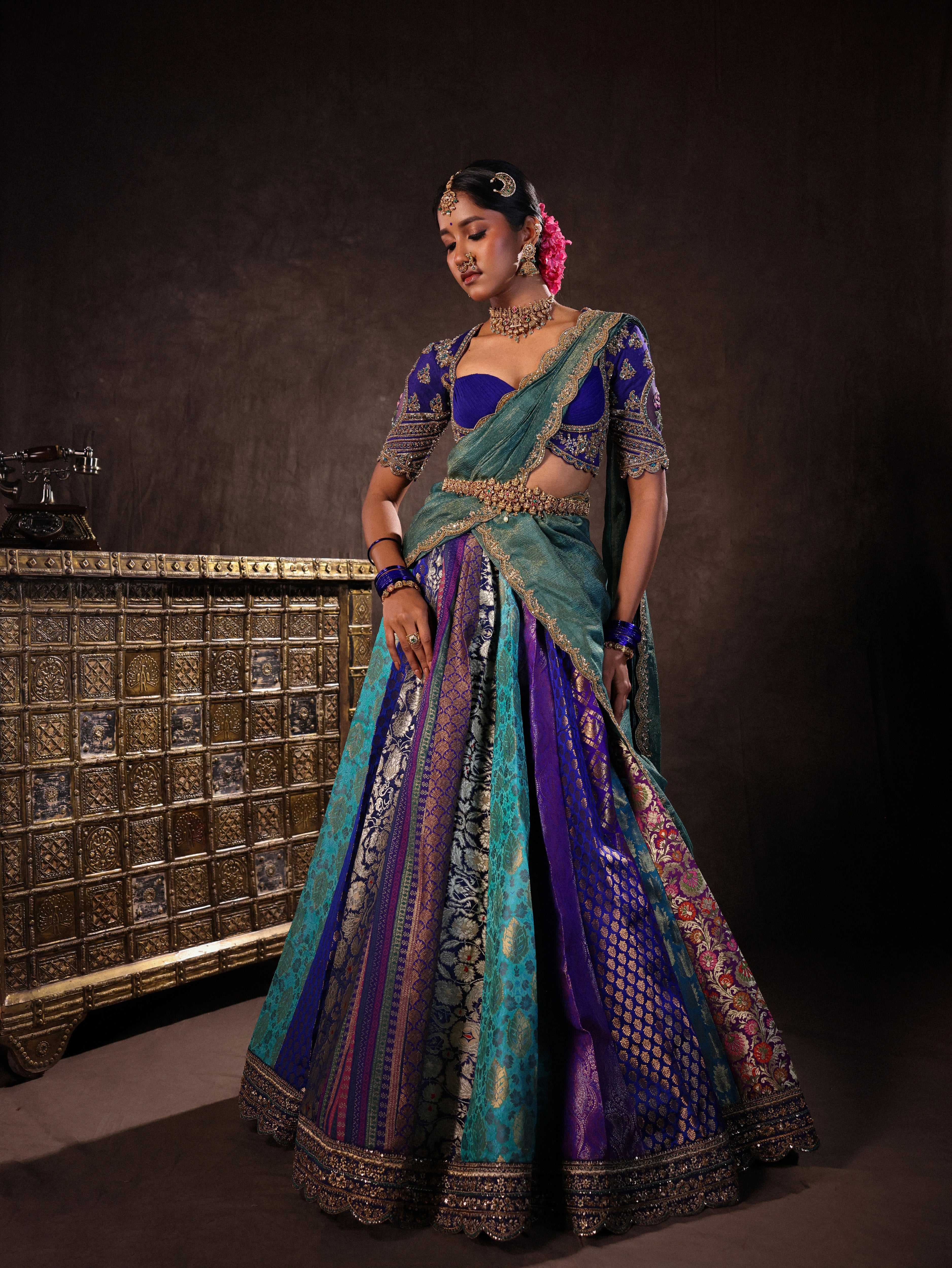 Model Gayathri Dhanasekar in a brocade, raw silk and tissue silk half saree set in shades of blue handcrafted with zardozi, resham, sequins and rhinestones. Team Archana Karthick completed the style with blue glass bangles, a ring, a choker, jhumkas, nose ring and a maang tikka.