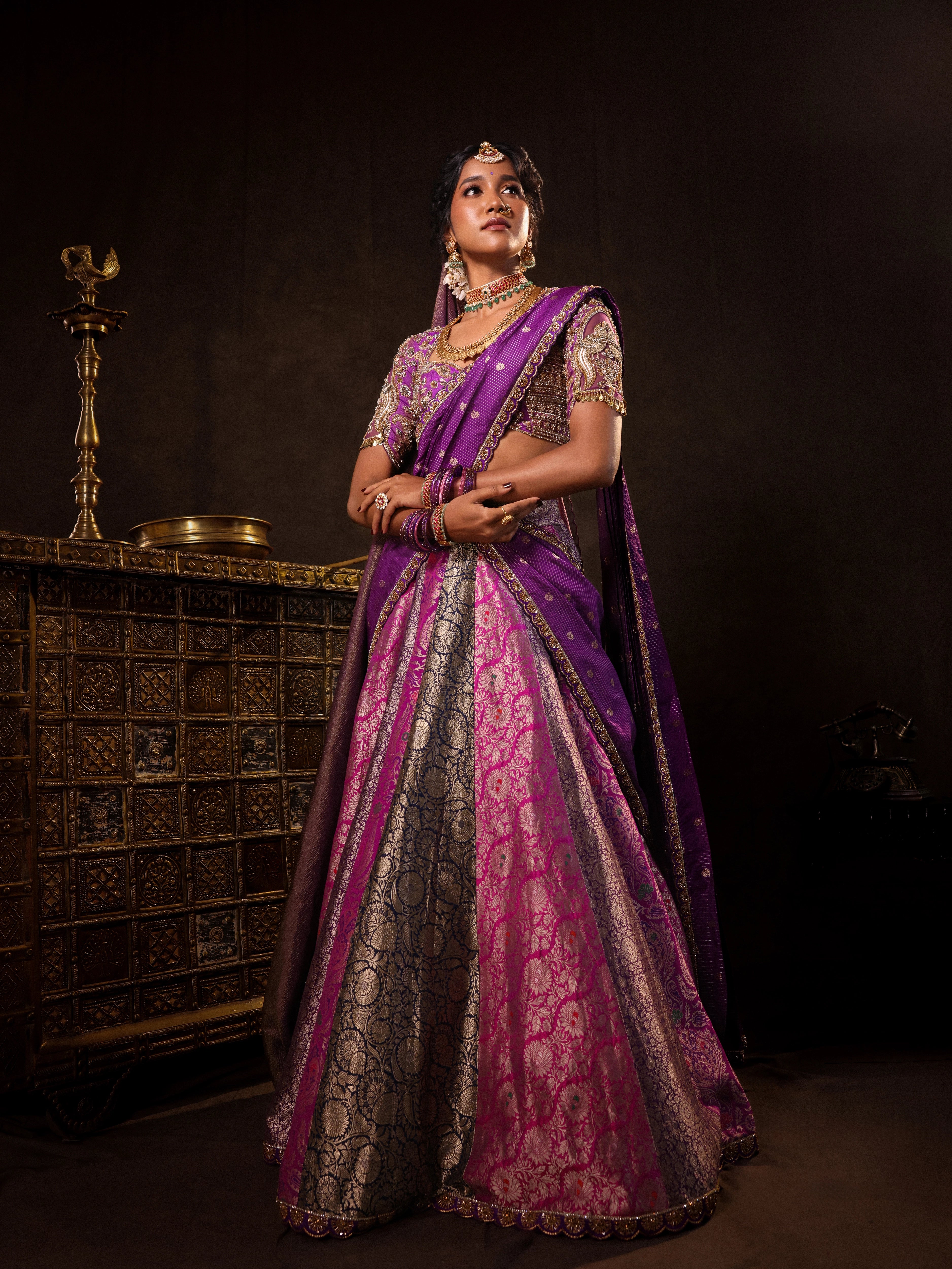 Model Gayathri Dhanasekar posing during photoshoot in a silk half saree in shades of purple with a scalloped veil is handrcrafted with sequins, cutdana, resham, stones and exquisite hangings by team Archana Karthick.