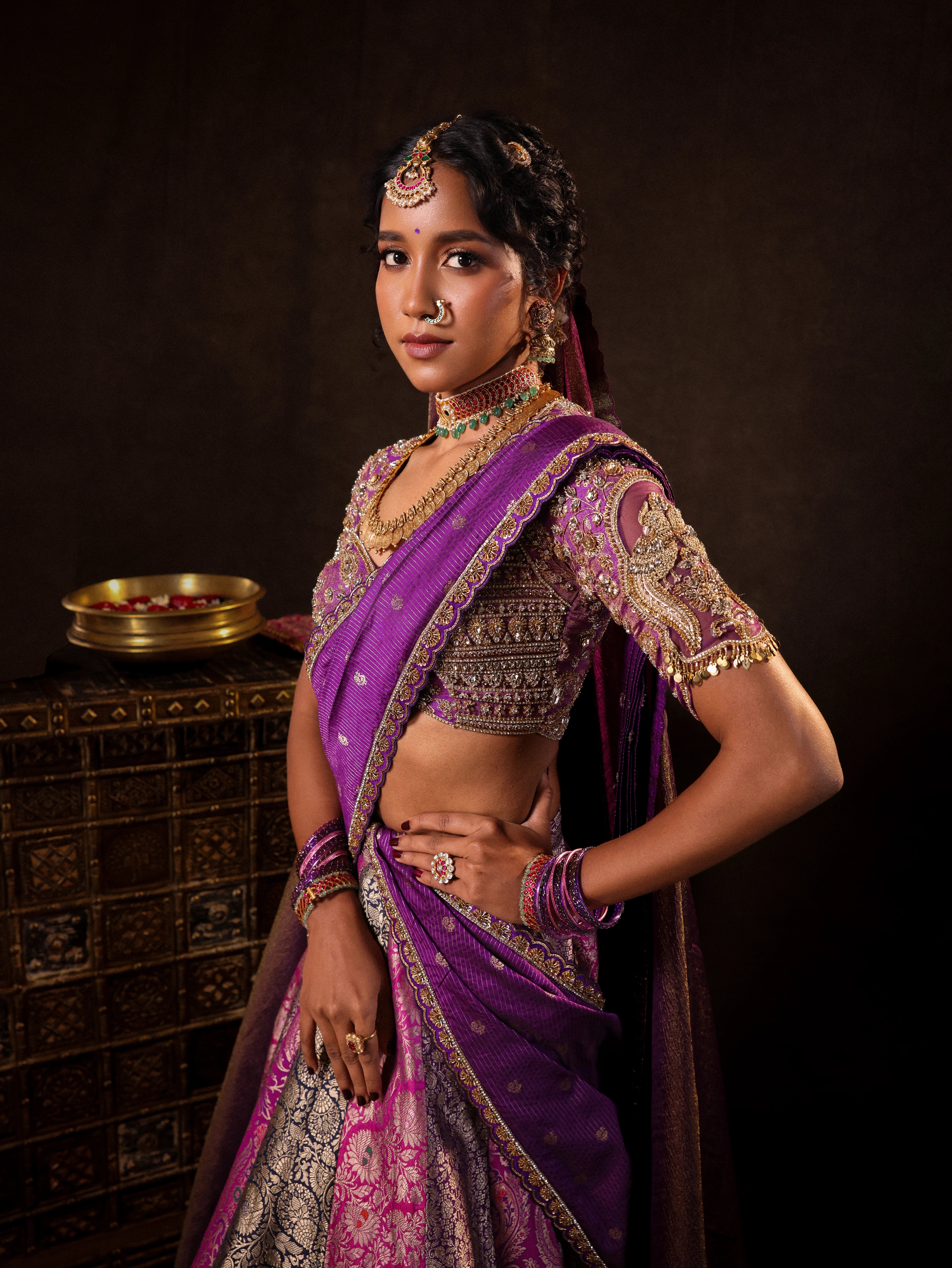 Model Gayathri Dhanasekar posing for side profile in a silk half saree in shades of purple with a scalloped veil is handrcrafted with sequins, cutdana, resham, stones and exquisite hangings by team Archana Karthick.