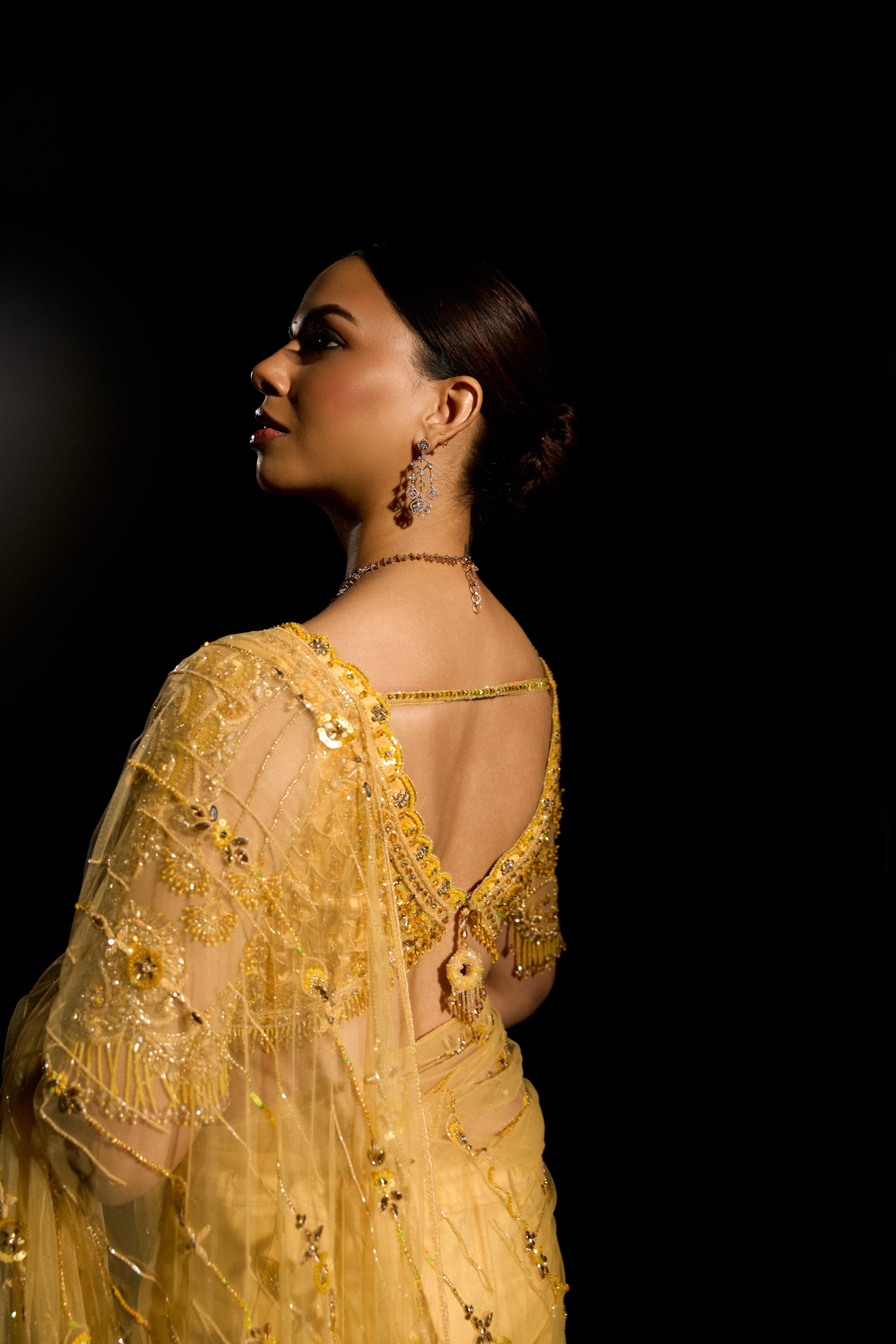 Model Jane C Thompson posing for back blouse design in a yellow saree set intricately adorned with sequins, rhinestones, crystals and cutdana for "STARDUST" - A/W'25 saree collection by team Archana Karthick.
