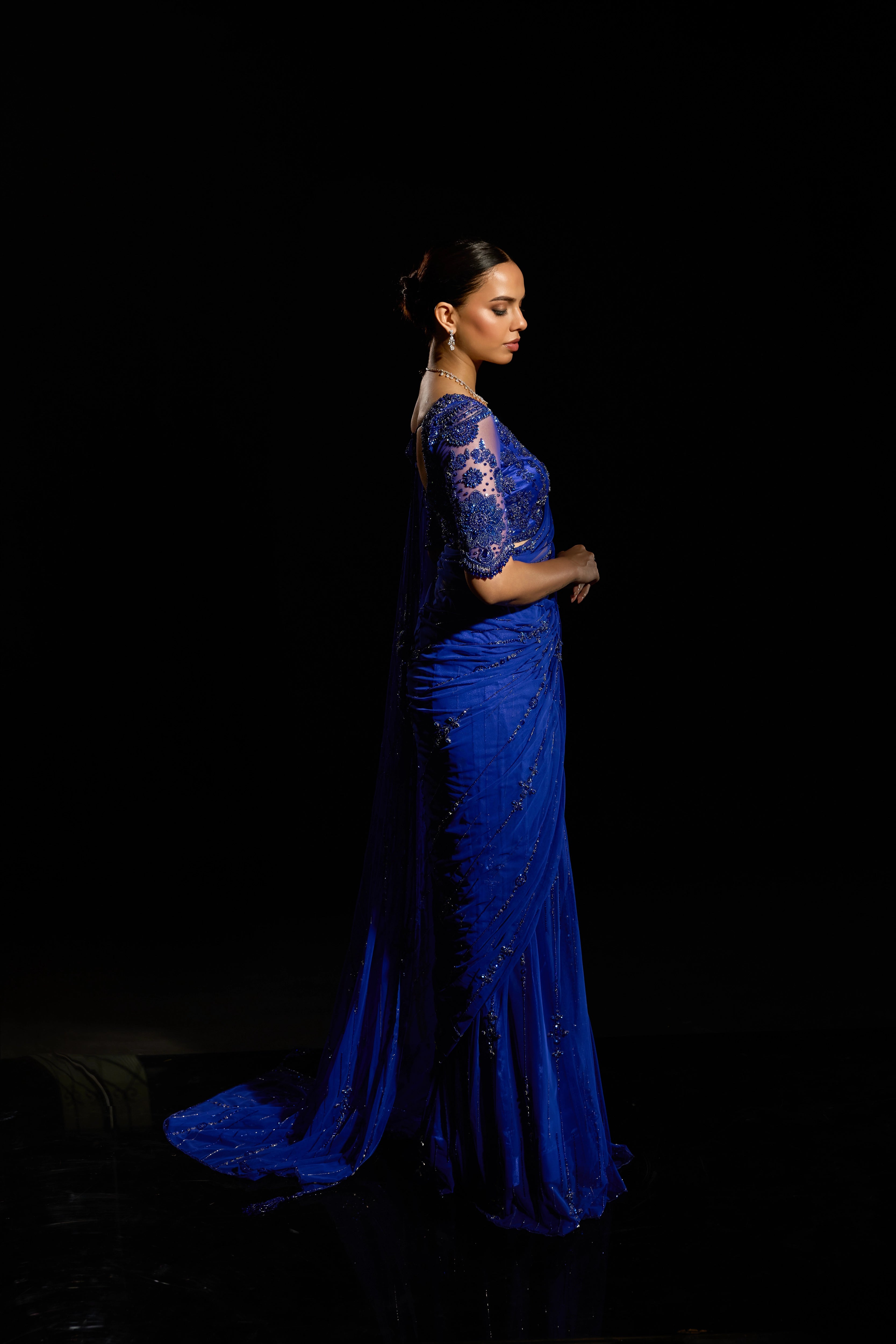Model Jane C Thompson posing for side profile in a sapphire blue saree set intricately adorned with sequins, rhinestones, crystals and cutdana for "STARDUST" - A/W'25 saree collection by team Archana Karthick.