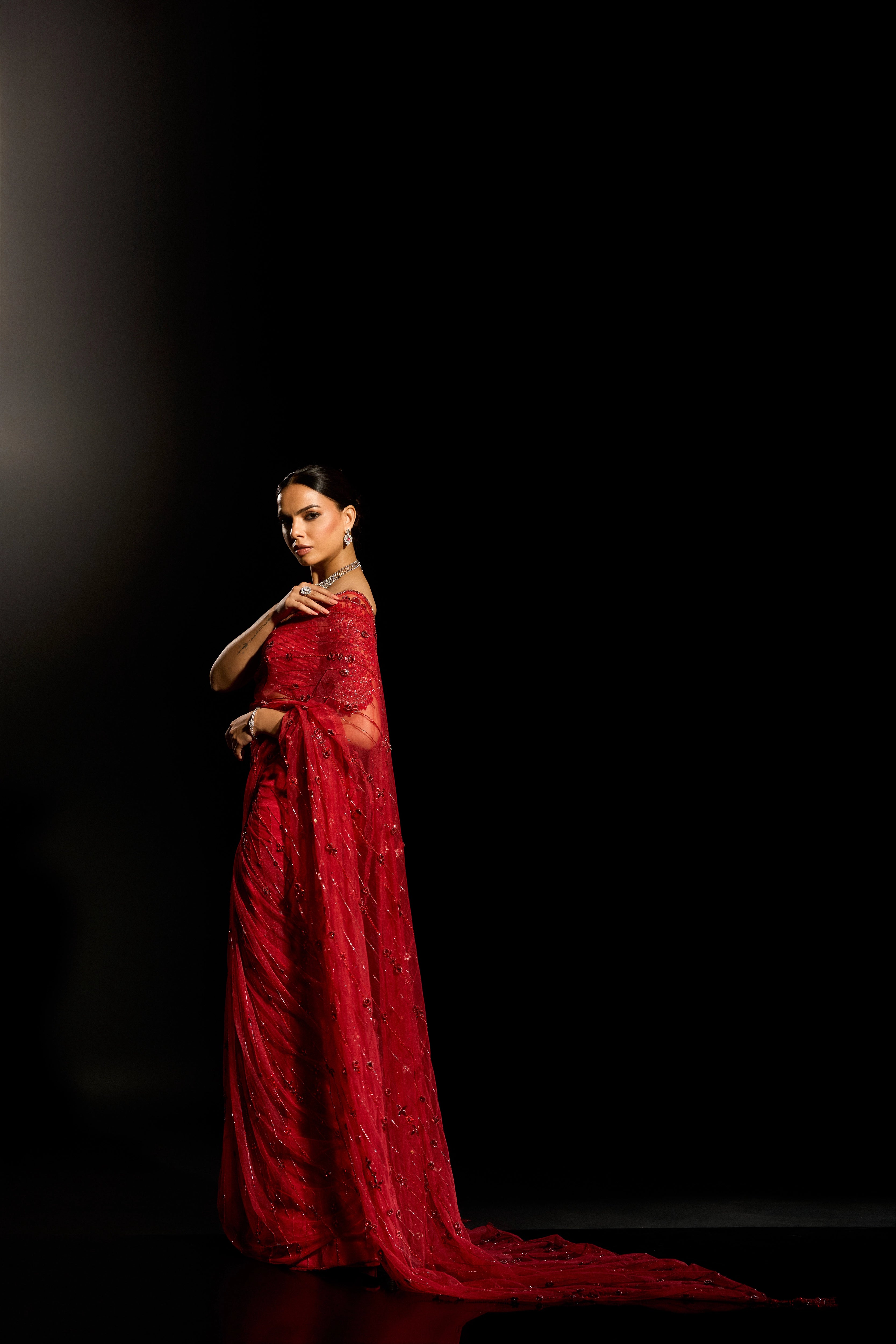 Model Jane C Thompson posing in a red saree set intricately adorned with sequins, rhinestones, crystals and cutdana for "STARDUST" - A/W'25 saree collection by team Archana Karthick.