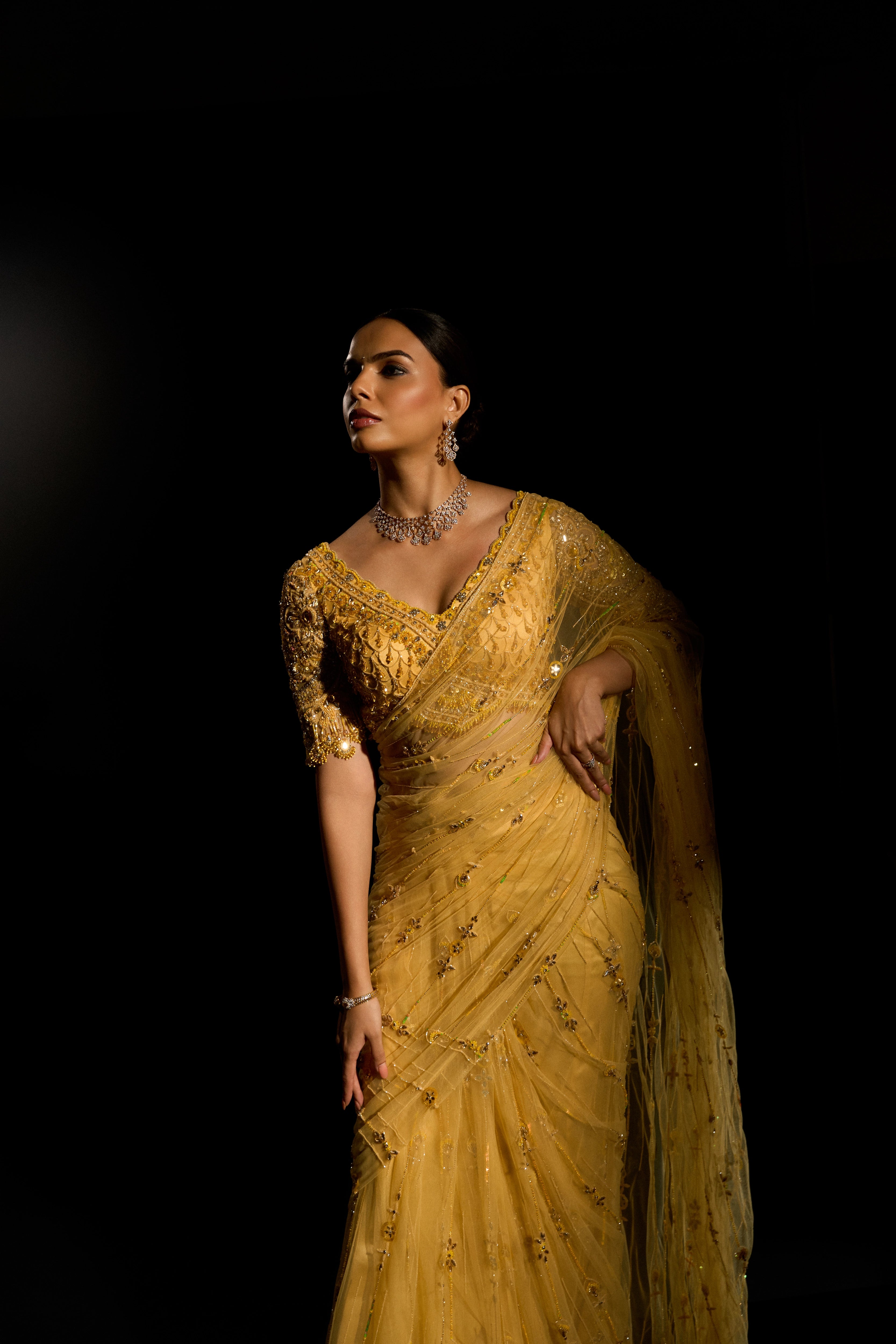 Model Jane C Thompson posing in a yellow saree set intricately adorned with sequins, rhinestones, crystals and cutdana for "STARDUST" - A/W'25 saree collection by team Archana Karthick.