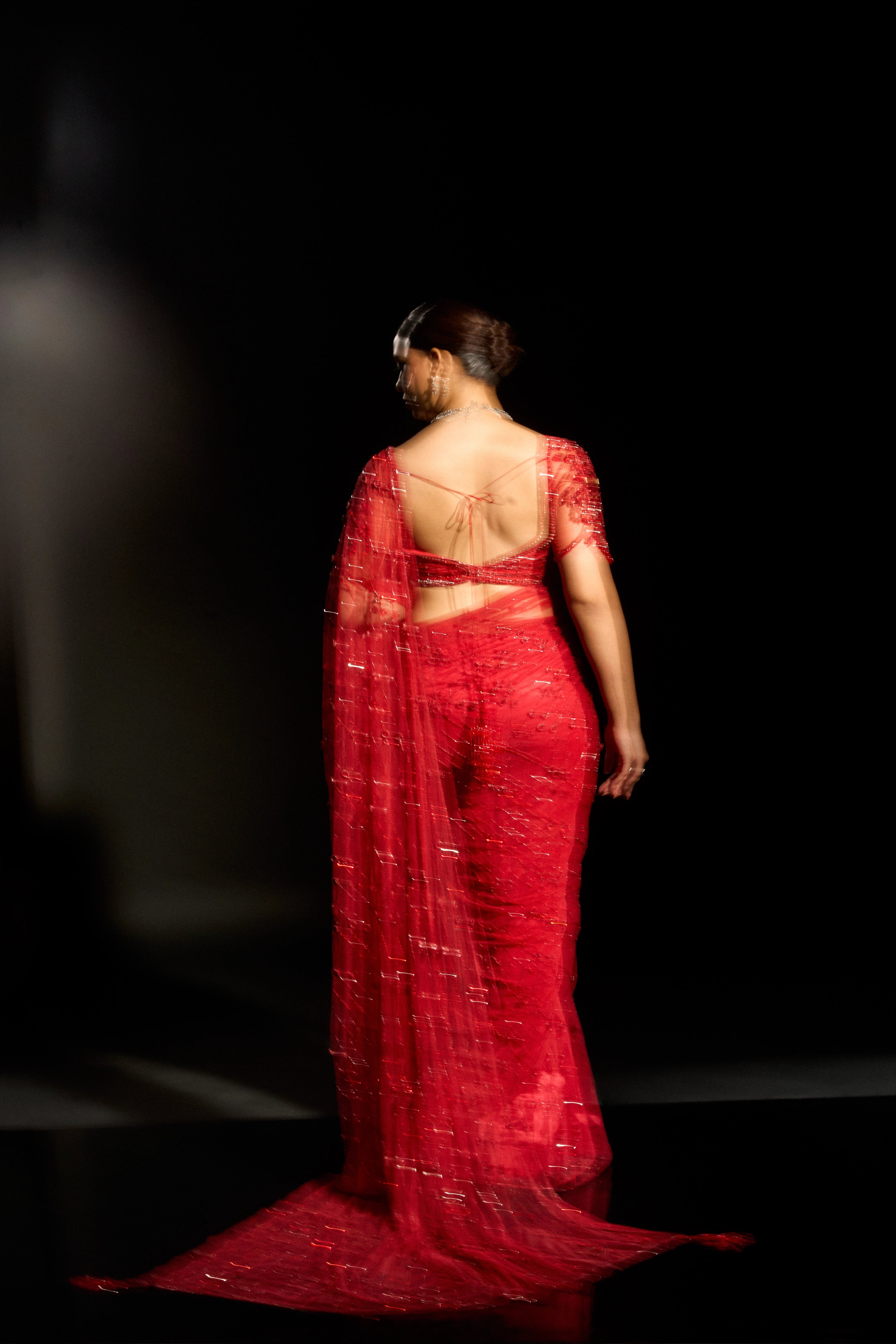 Model Jane C Thompson showcasing back design in a red saree set intricately adorned with sequins, rhinestones, crystals and cutdana for "STARDUST" - A/W'25 saree collection by team Archana Karthick.