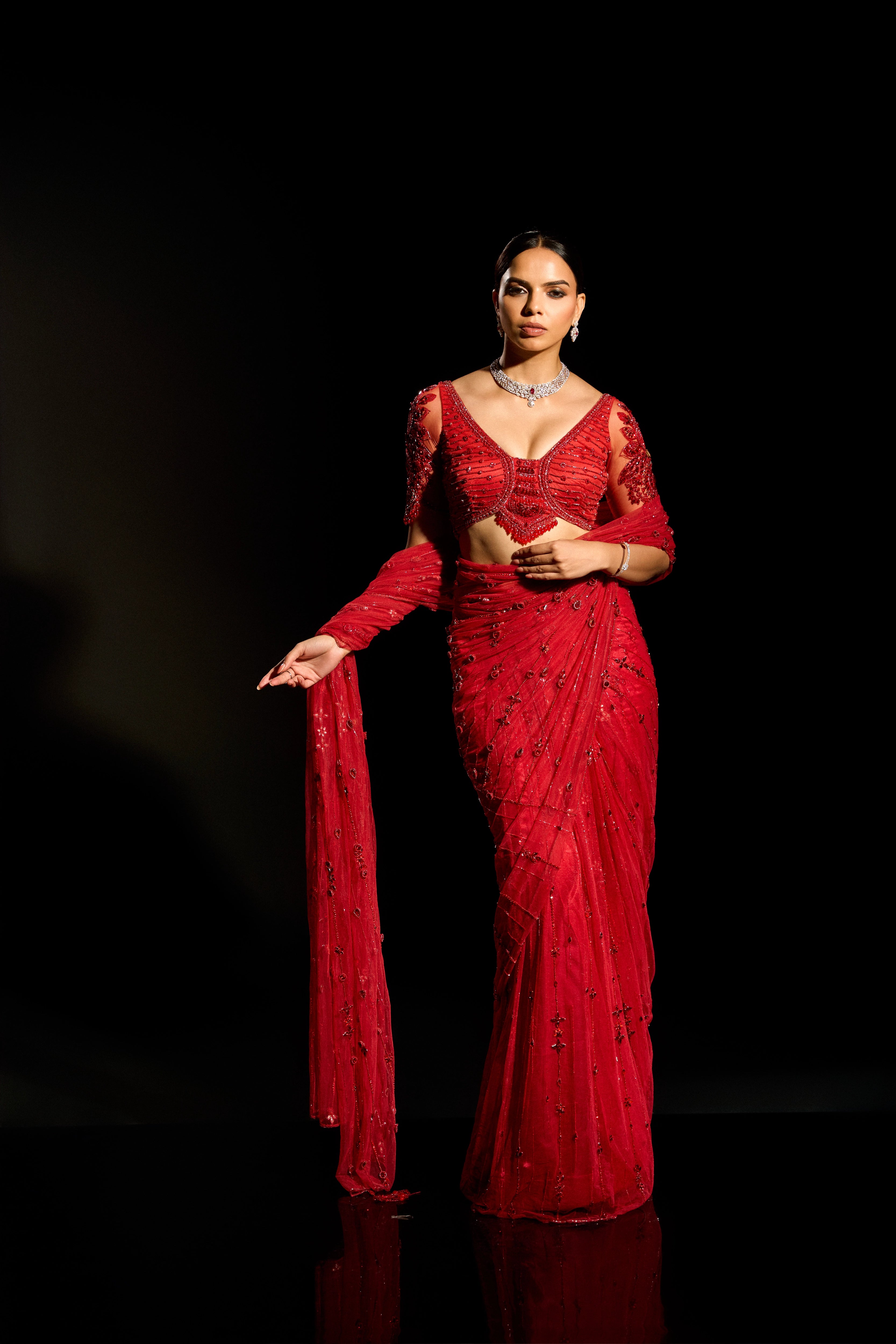 Model Jane C Thompson showcasing front blouse and saree design in a red saree set intricately adorned with sequins, rhinestones, crystals and cutdana for "STARDUST" - A/W'25 saree collection by team Archana Karthick.