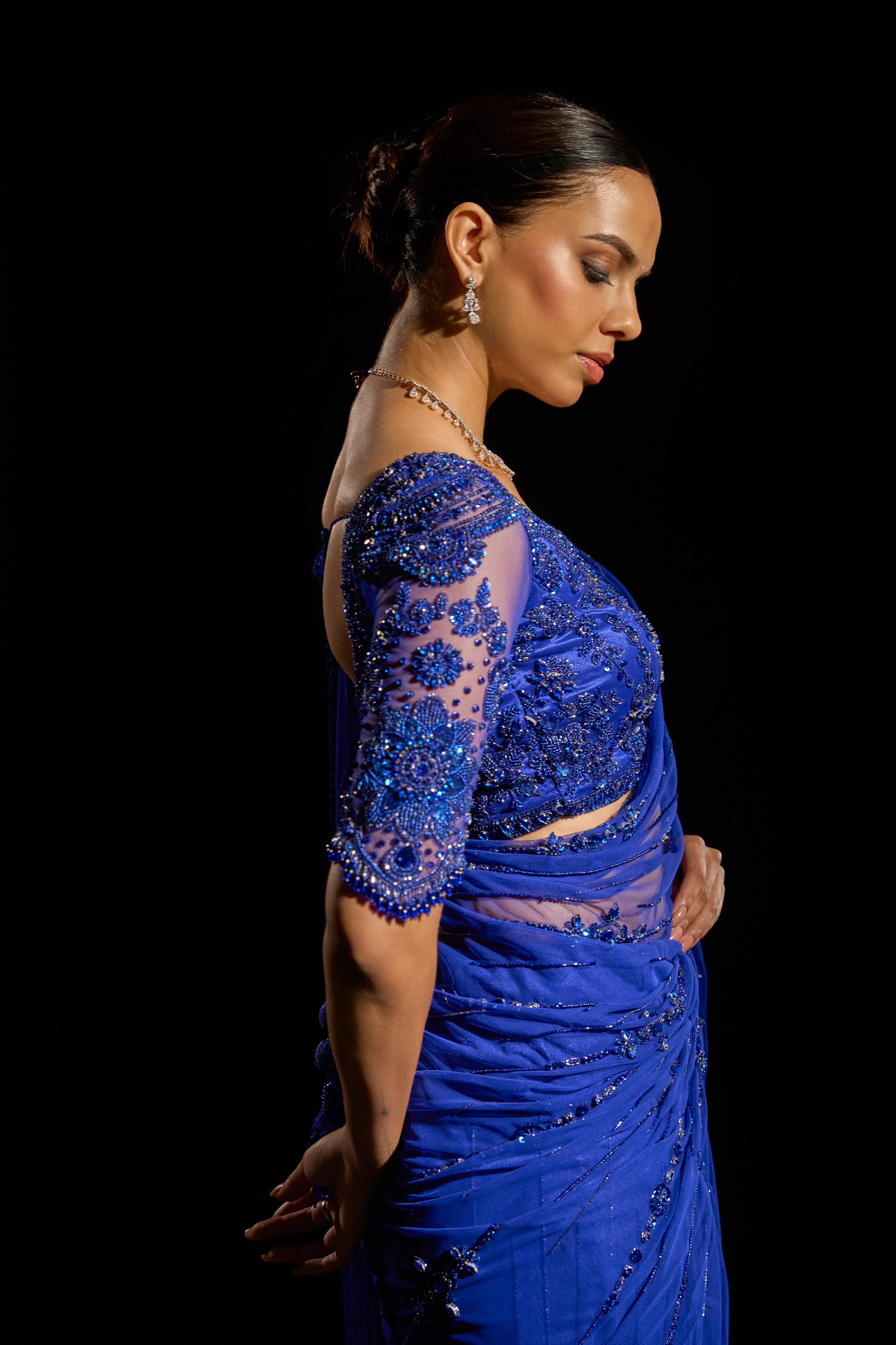 Model Jane C Thompson showcasing side profile detailing in a sapphire blue saree set intricately adorned with sequins, rhinestones, crystals and cutdana for "STARDUST" - A/W'25 saree collection by team Archana Karthick.