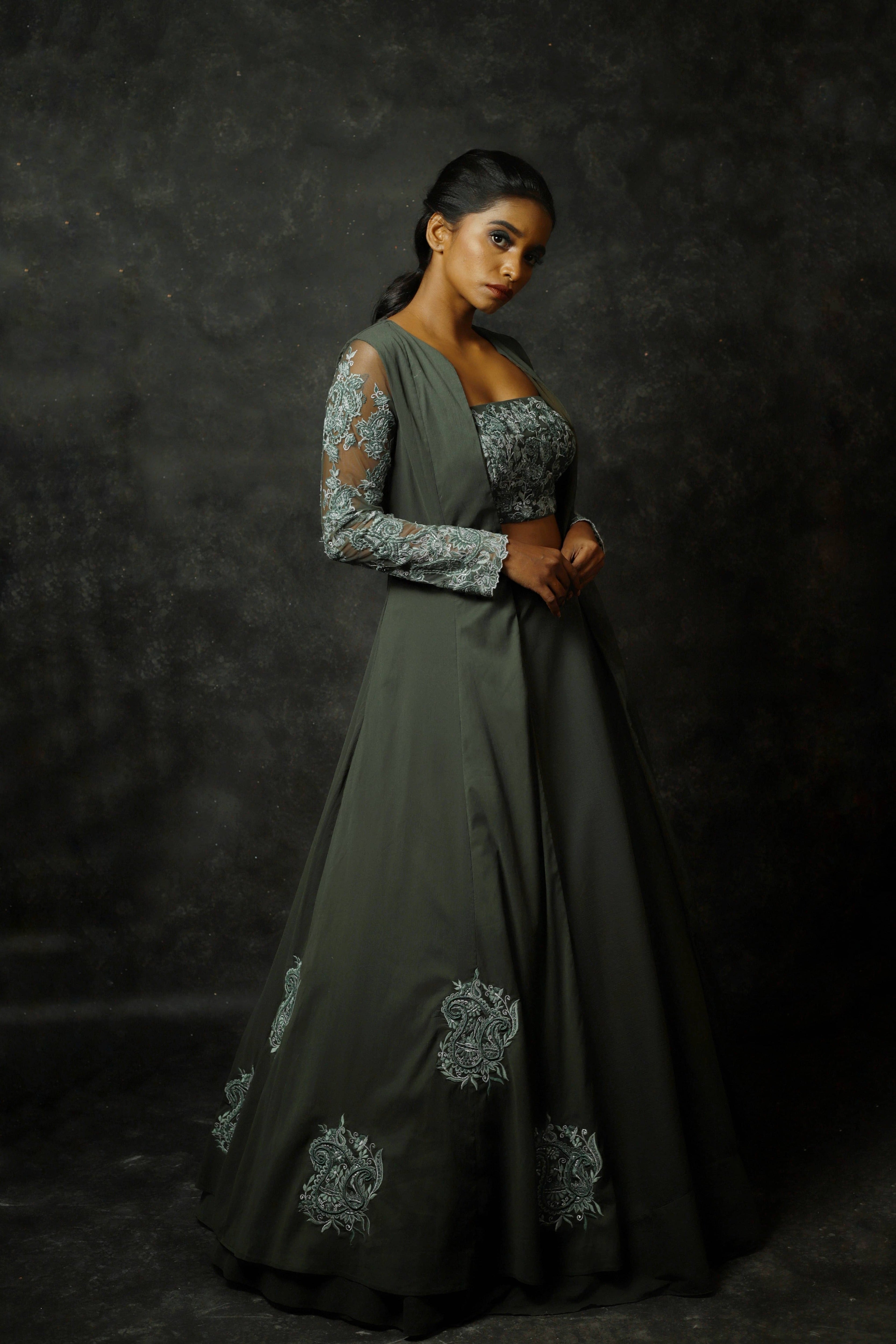 Model Posing in an olive green georgette masakali lehenga with long shrug and bralette