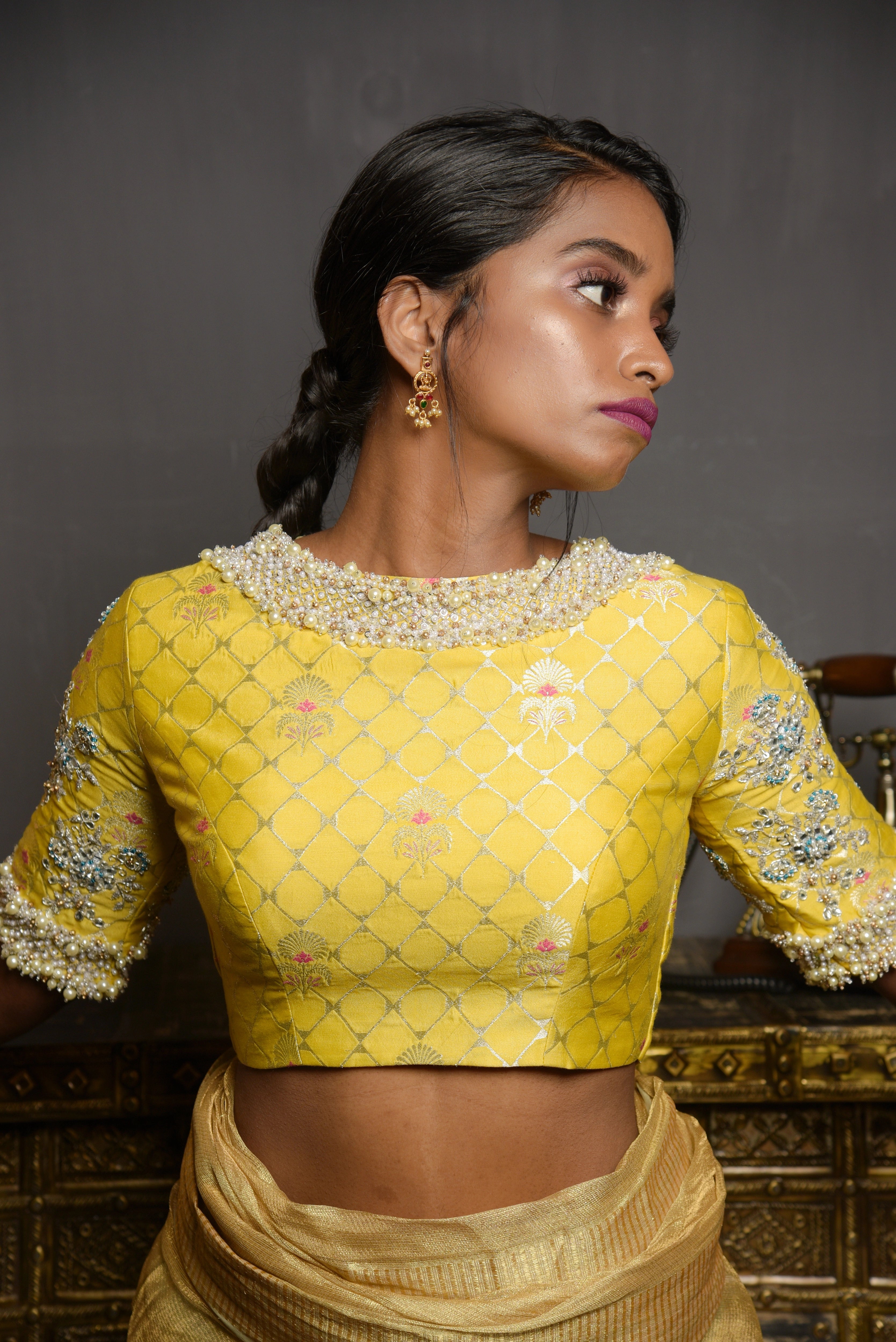 Model Pravallika Prasanna Raju is posing for front blouse design in a yellow banarasi silk blouse with pearl embellishments on sleeves.
