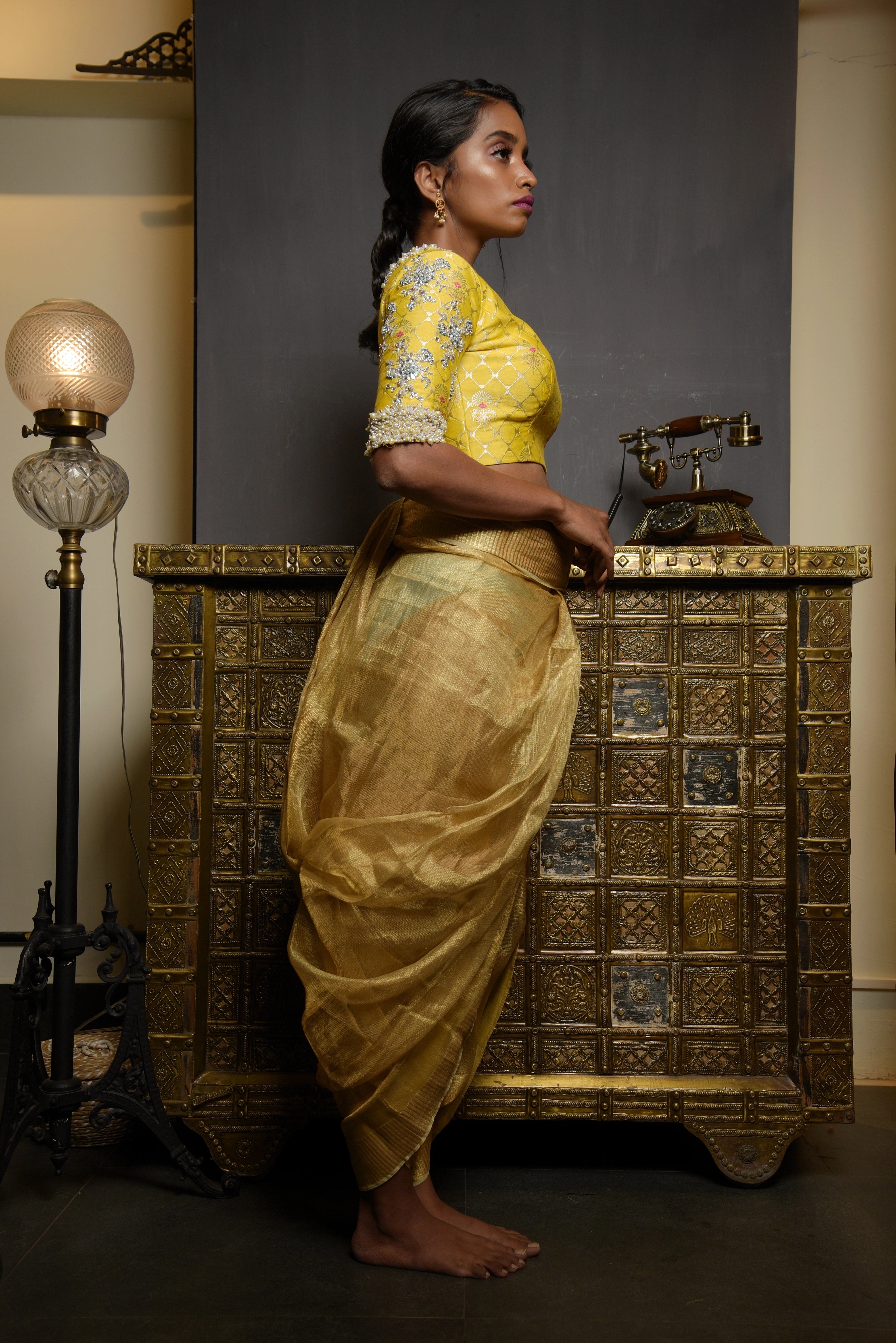 Model Pravallika Prasanna Raju posing for full side profile in a yellow banarasi silk blouse with pearl embellishments on sleeves.