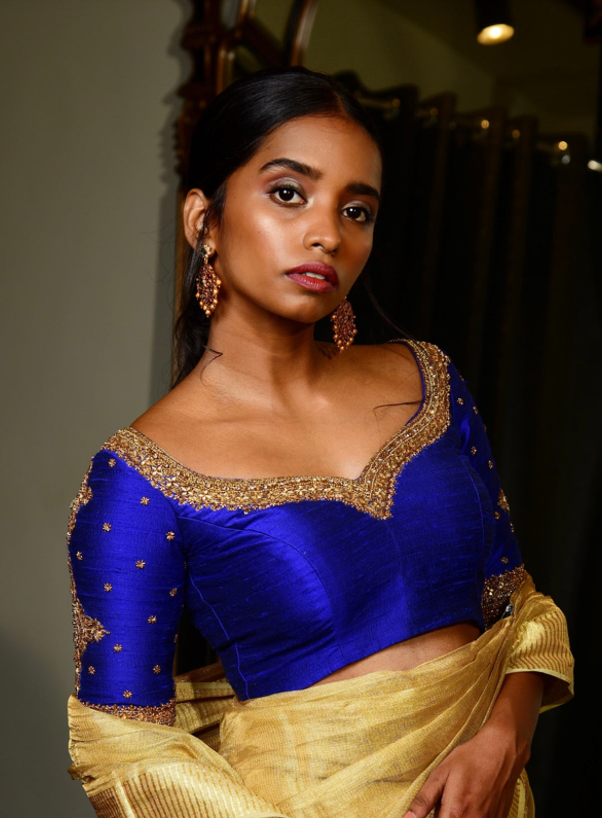 Model Pravallika Prasanna Raju posing for photoshoot in a handcrafted raw silk blouse in blue with intricate zardozi work on the sleeves and neckline designed by Archana Karthick.