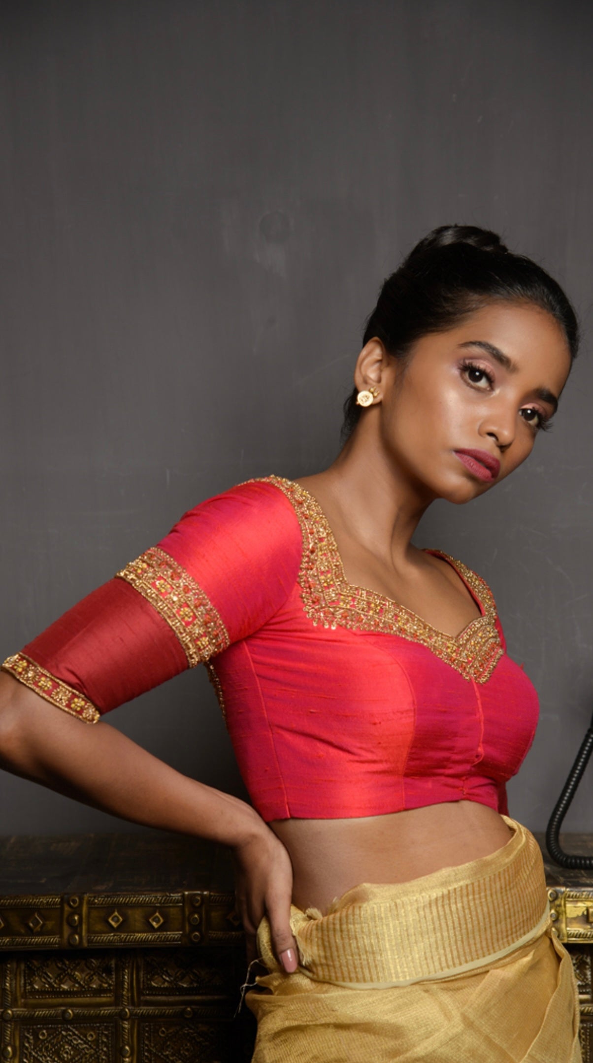 Model Pravallika Prasanna Raju posing for photoshoot in a red raw silk blouse, intricately handcrafted with pearls, zardozi, stones and zari by team Archana Karthick.