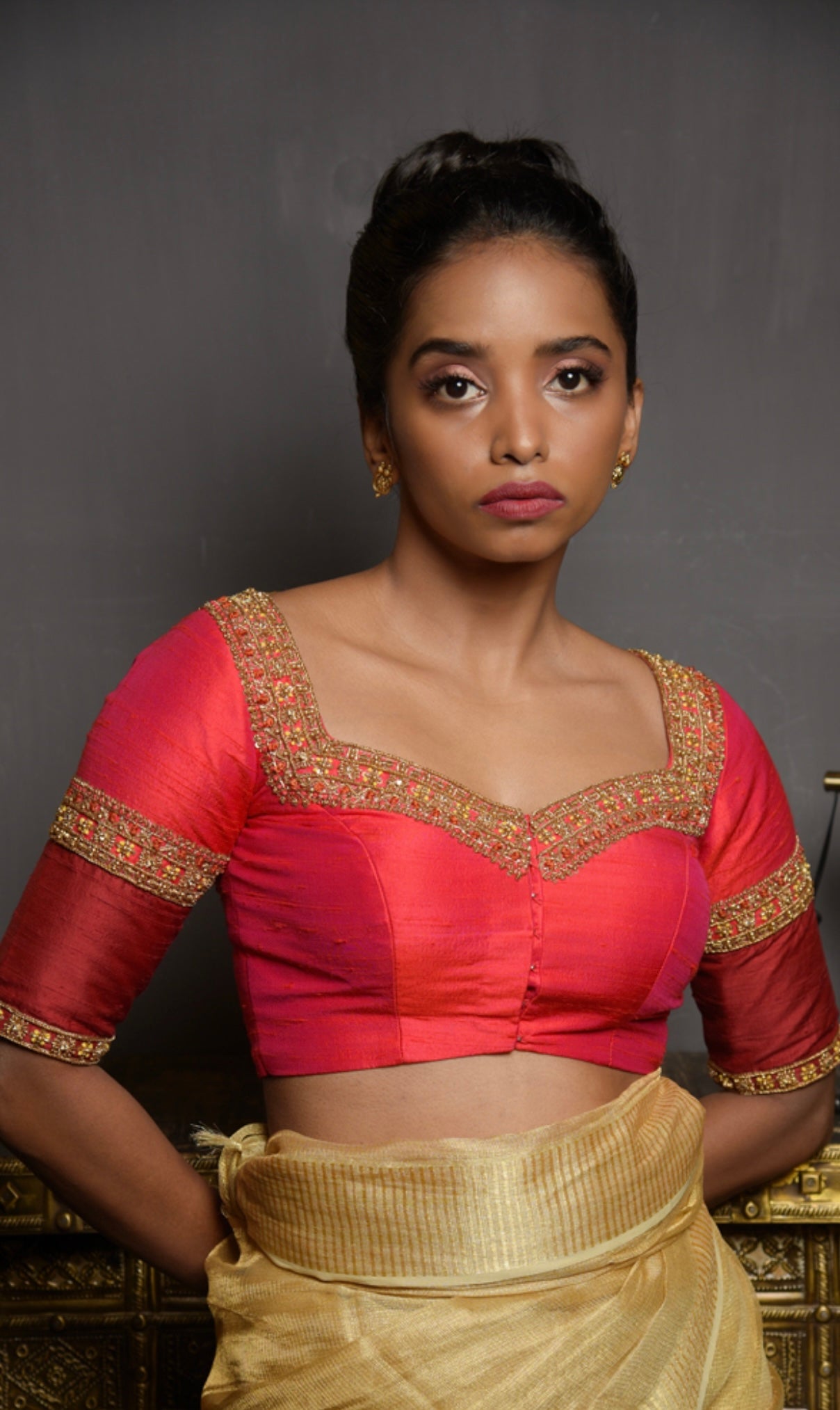 Model Pravallika Prasanna Raju posing in a red raw silk blouse, intricately handcrafted with pearls, zardozi, stones and zari by team Archana Karthick.
