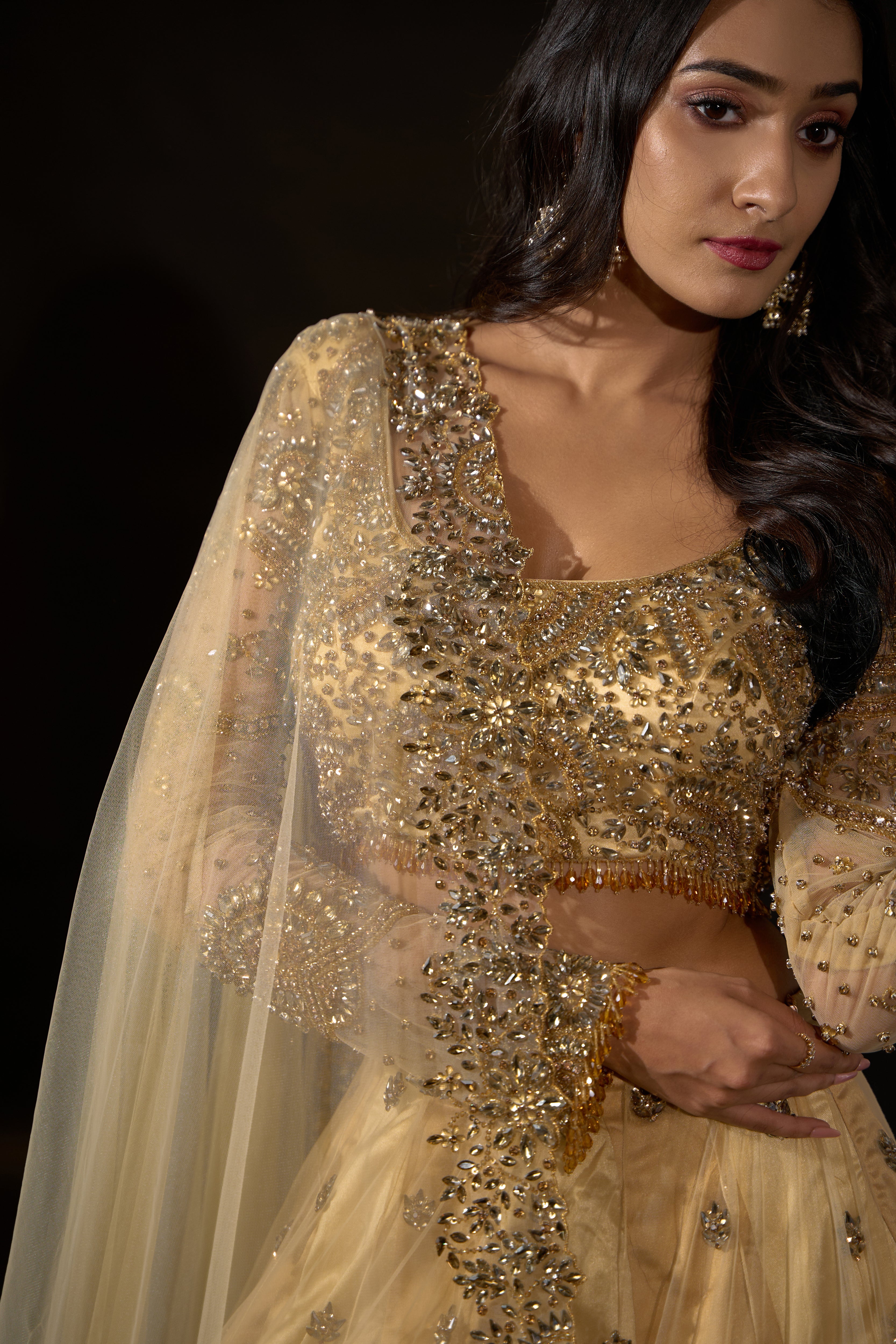Model Rheyea in a golden beige lehnega by Archana Karthick posing looking away from lens.