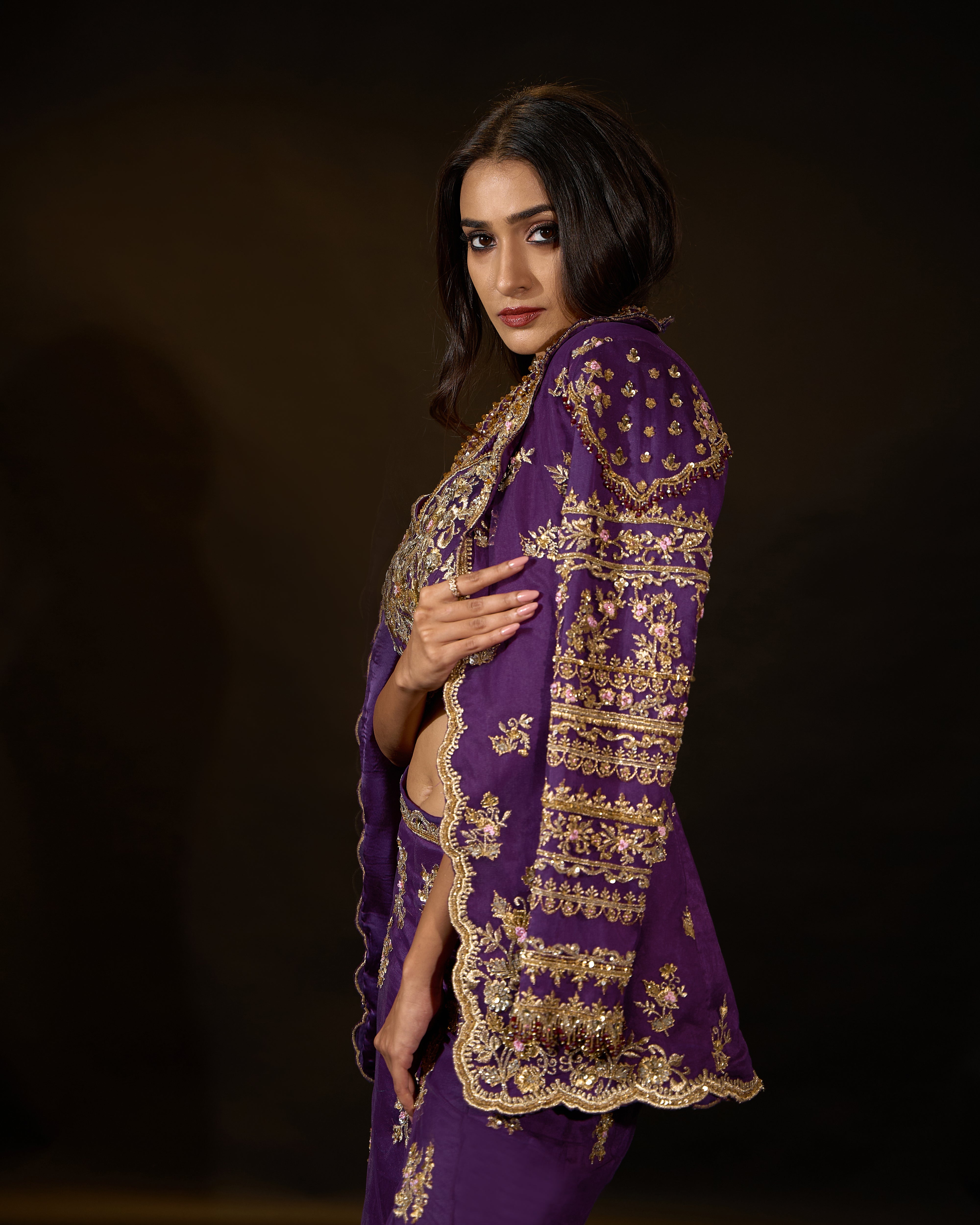 Model Rheyea in a purple jacket dress with bralette and palazzo pants. side profile jacket sleeve detailing.