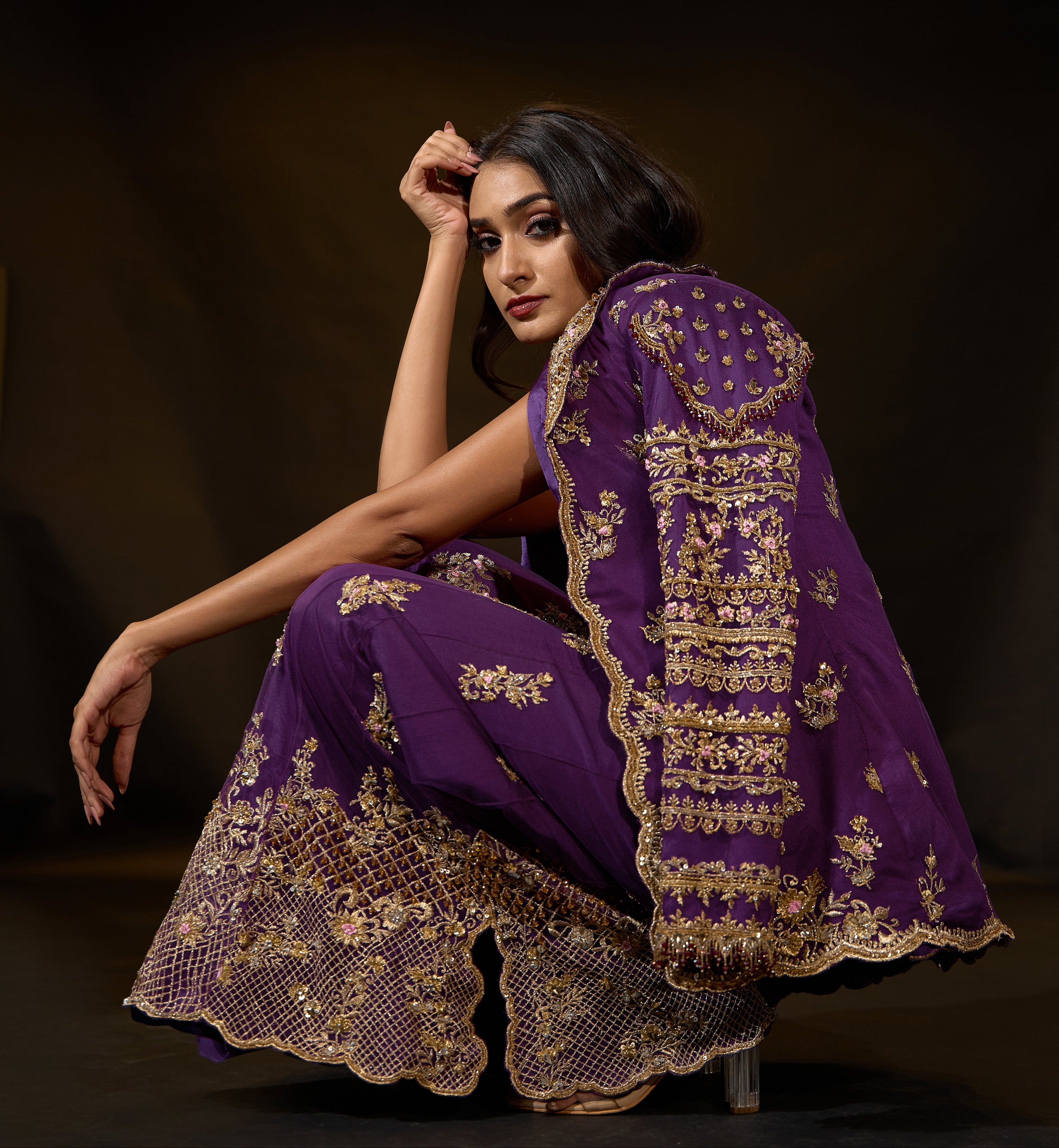Model Rheyea in a purple jacket dress with bralette and palazzo pants. squat pose