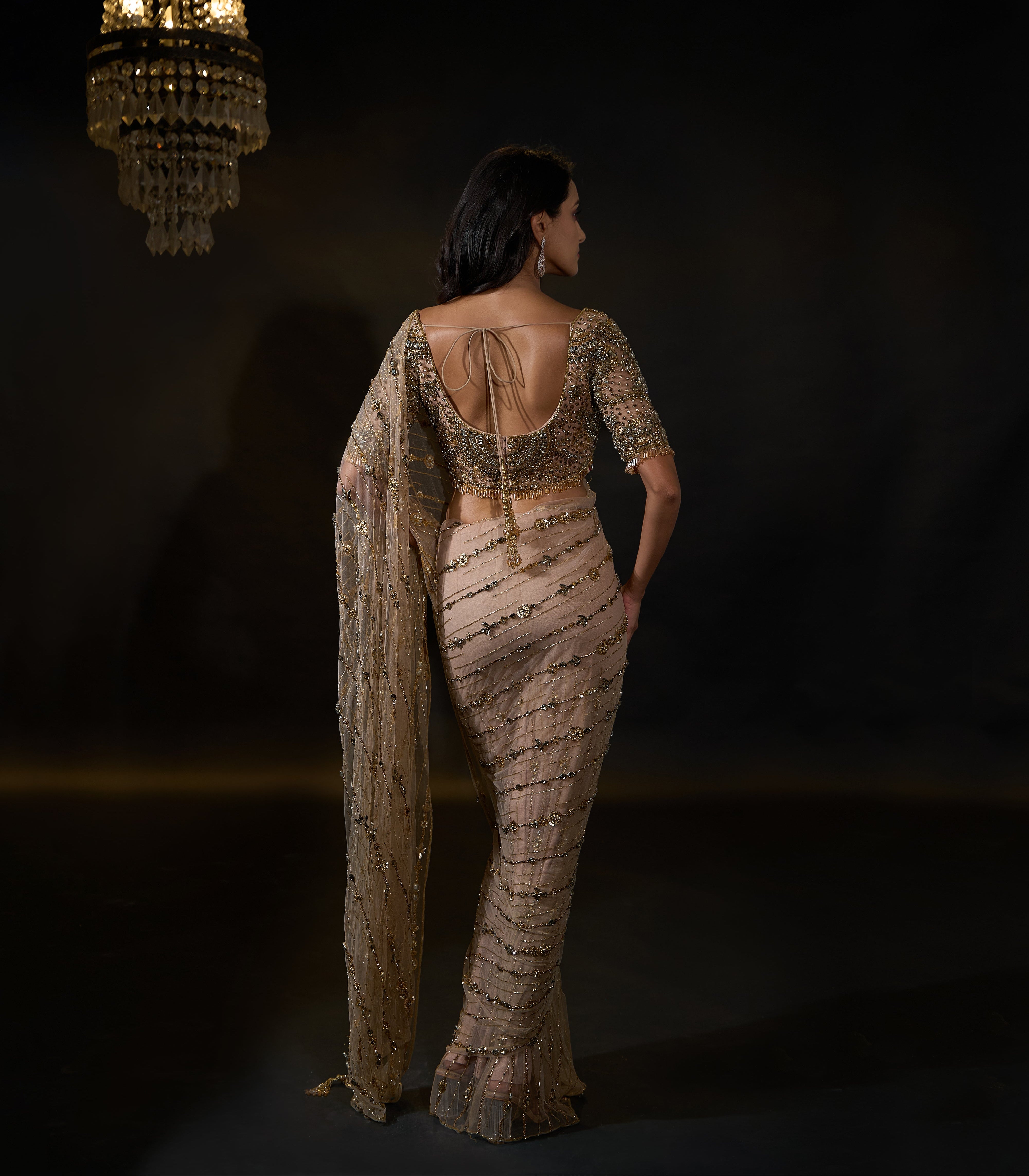Model Rheyea in signature golden beige handcrafted net saree paired with a heavily embellished blouse by Archana Karthick. Stone work all over back blouse design and saree pallu.