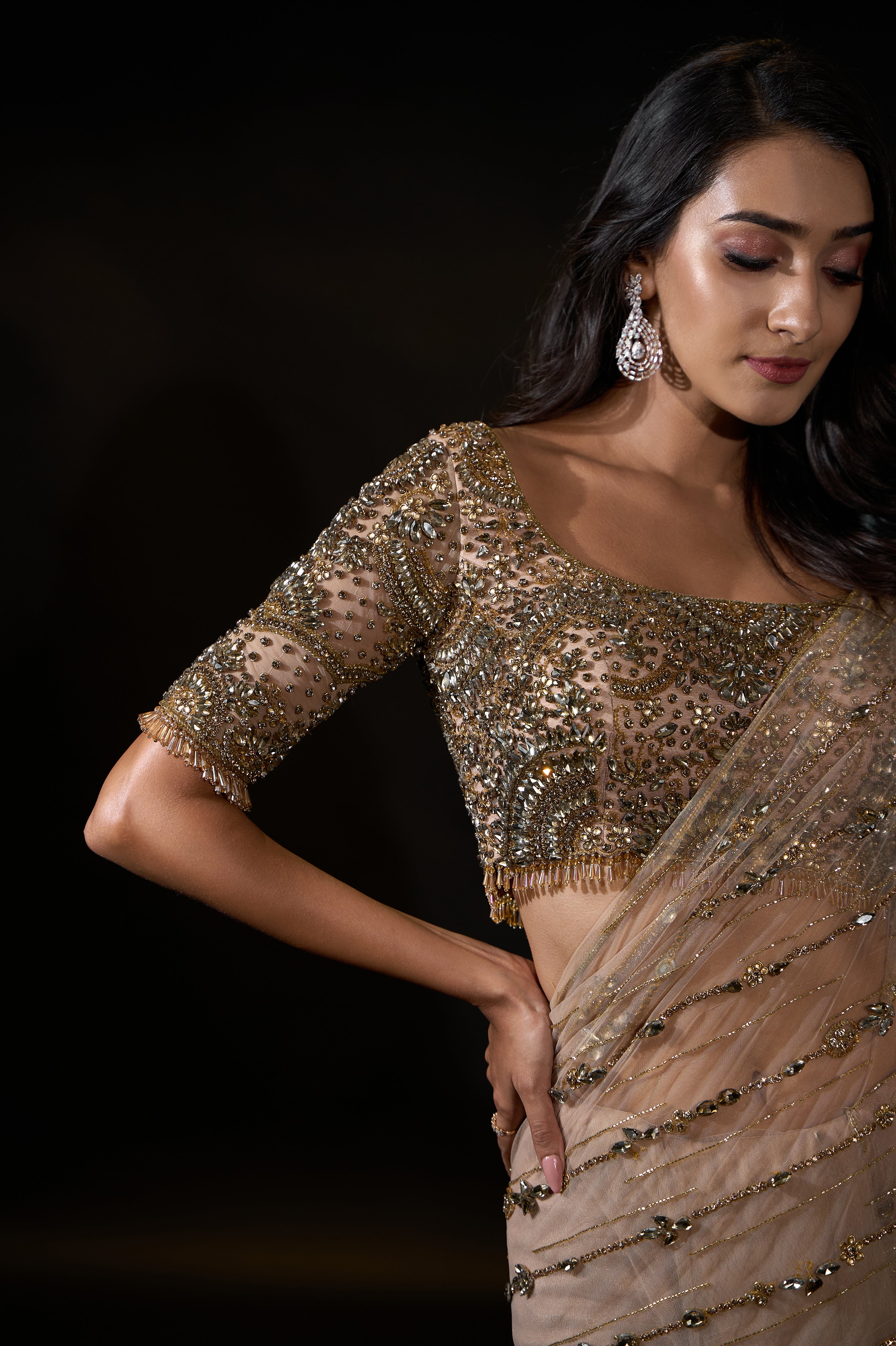 Model Rheyea in signature golden beige handcrafted net saree paired with a heavily embellished blouse by Archana Karthick. Stone work all over cups of blouse and hand on waist.