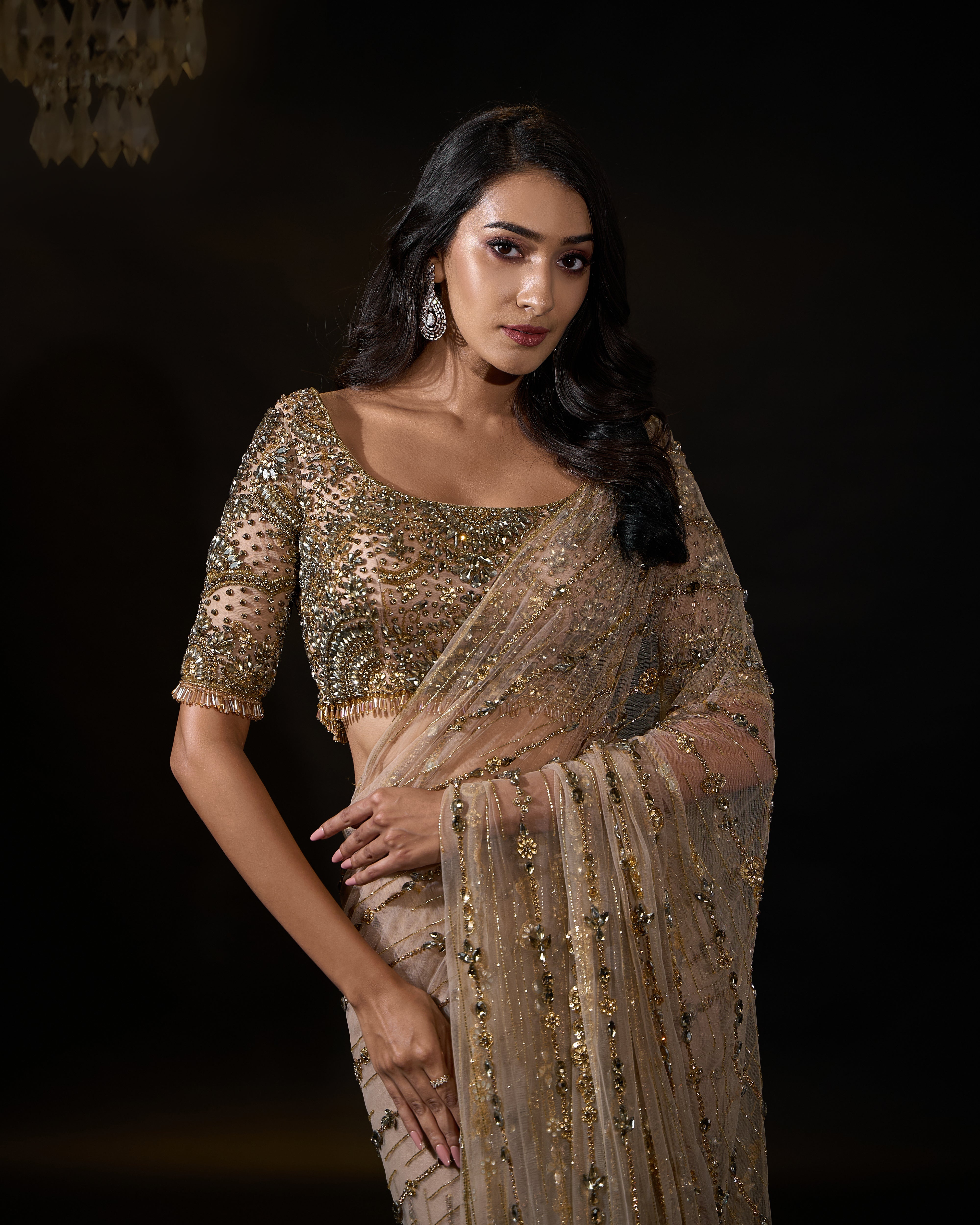 Model Rheyea in signature golden beige handcrafted net saree paired with a heavily embellished blouse by Archana Karthick. Stone work all over front blouse and hand over waist.