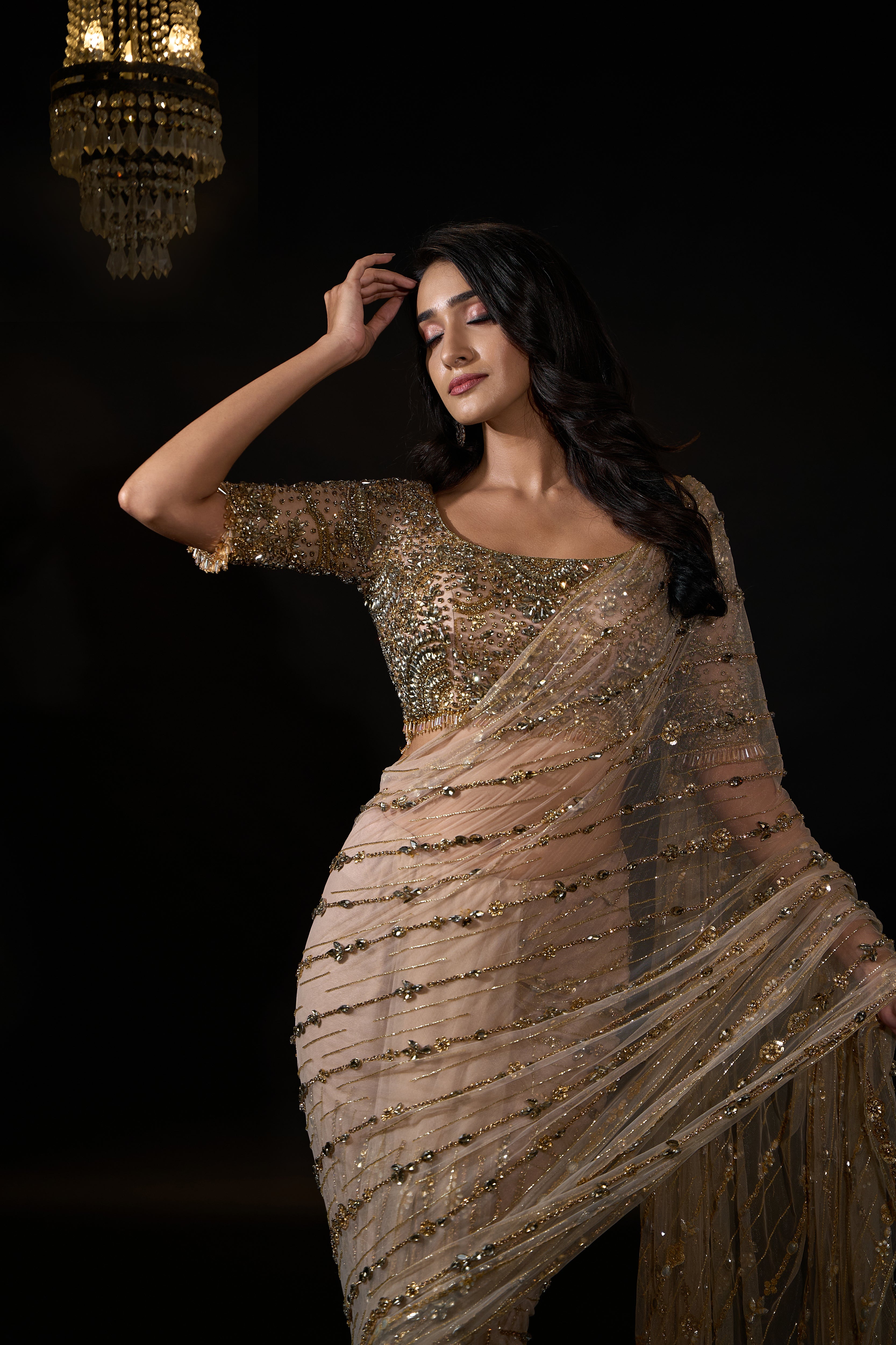 Model Rheyea in signature golden beige handcrafted net saree paired with a heavily embellished blouse by Archana Karthick. Stone work all over saree and blouse