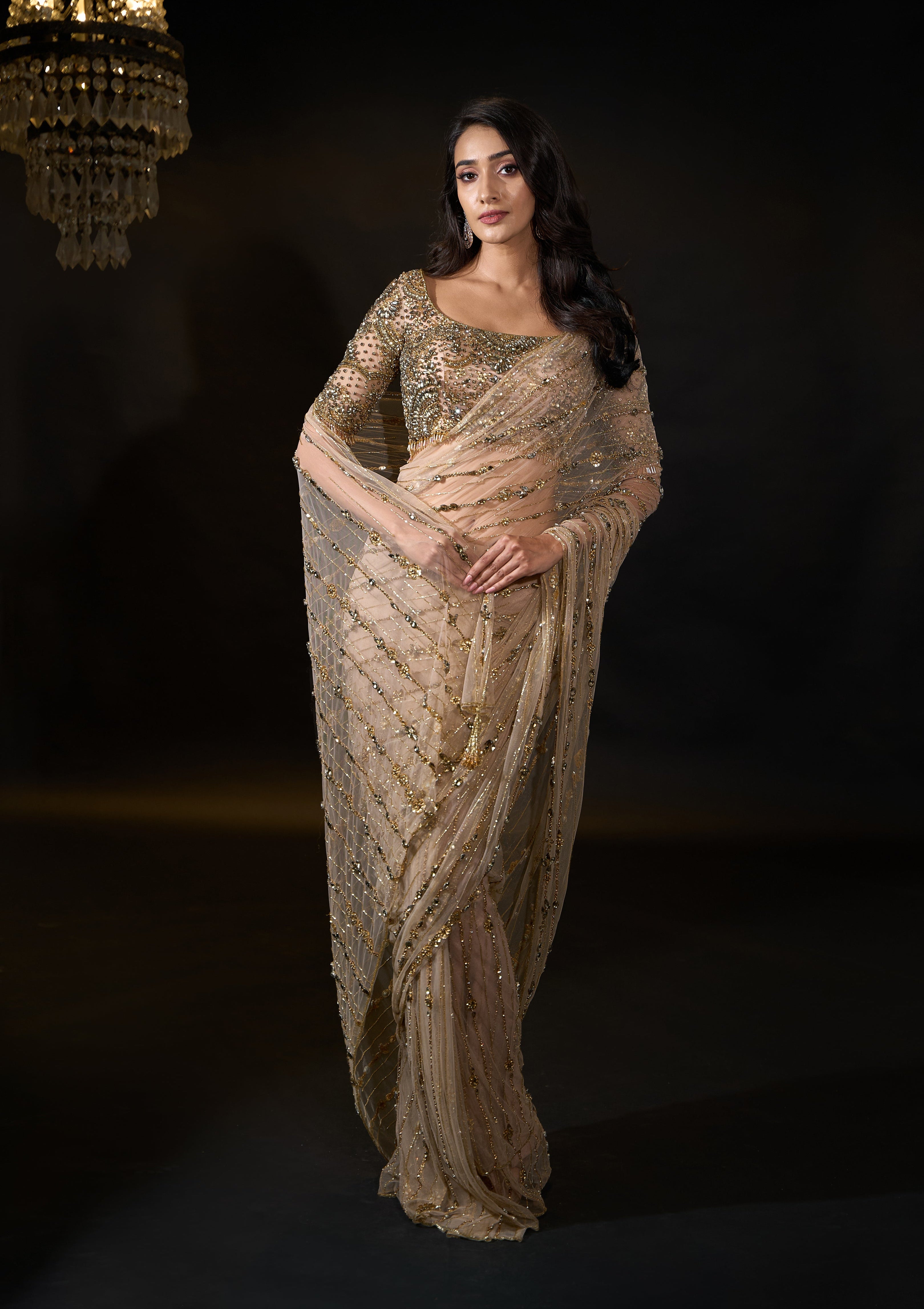 Model Rheyea in signature golden beige handcrafted net saree paired with a heavily embellished blouse by Archana Karthick. Stone work all over saree and blouse front pose