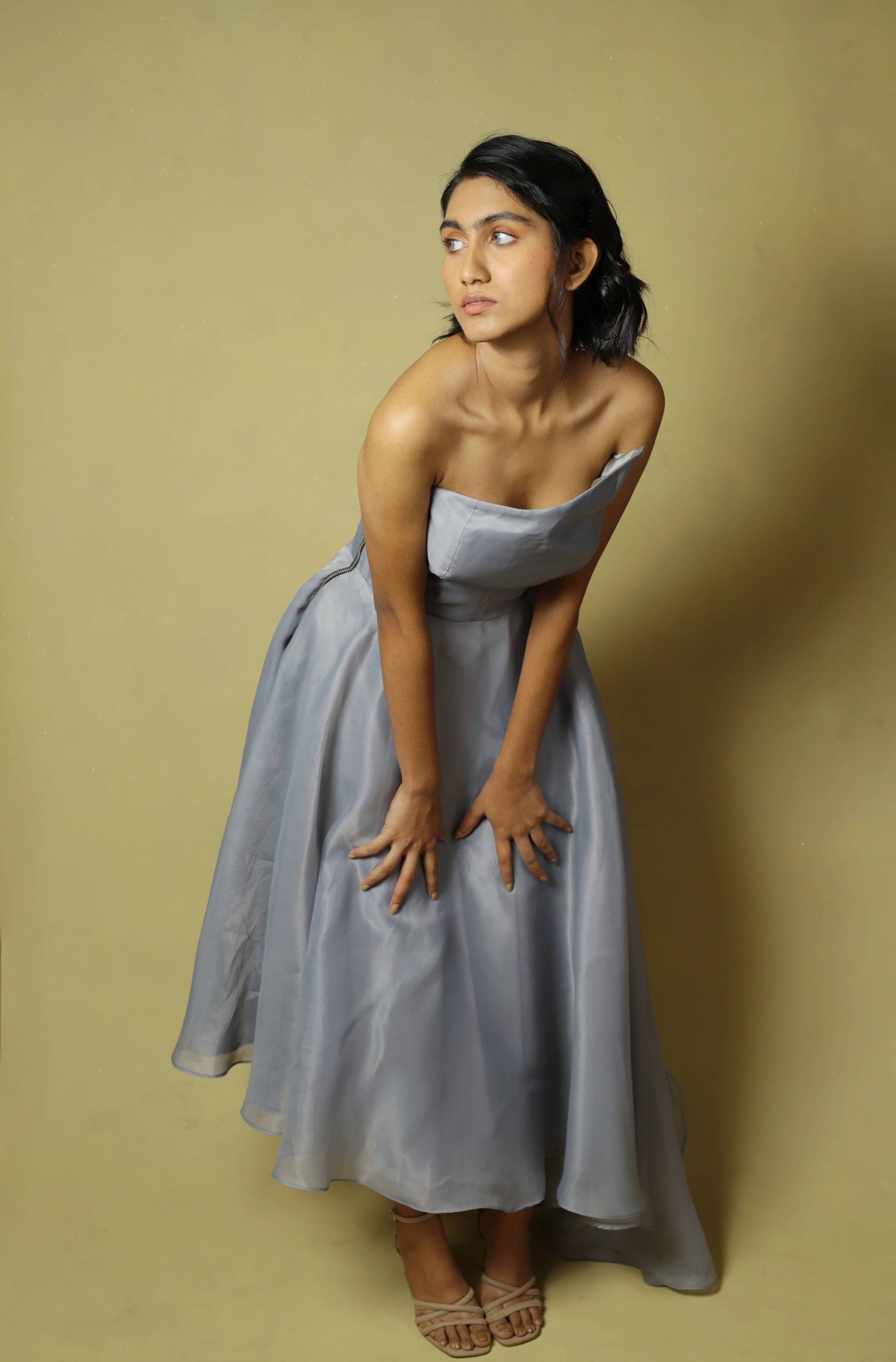 Model posing bent forward in a silver organza dress designed by Archana Karthick.