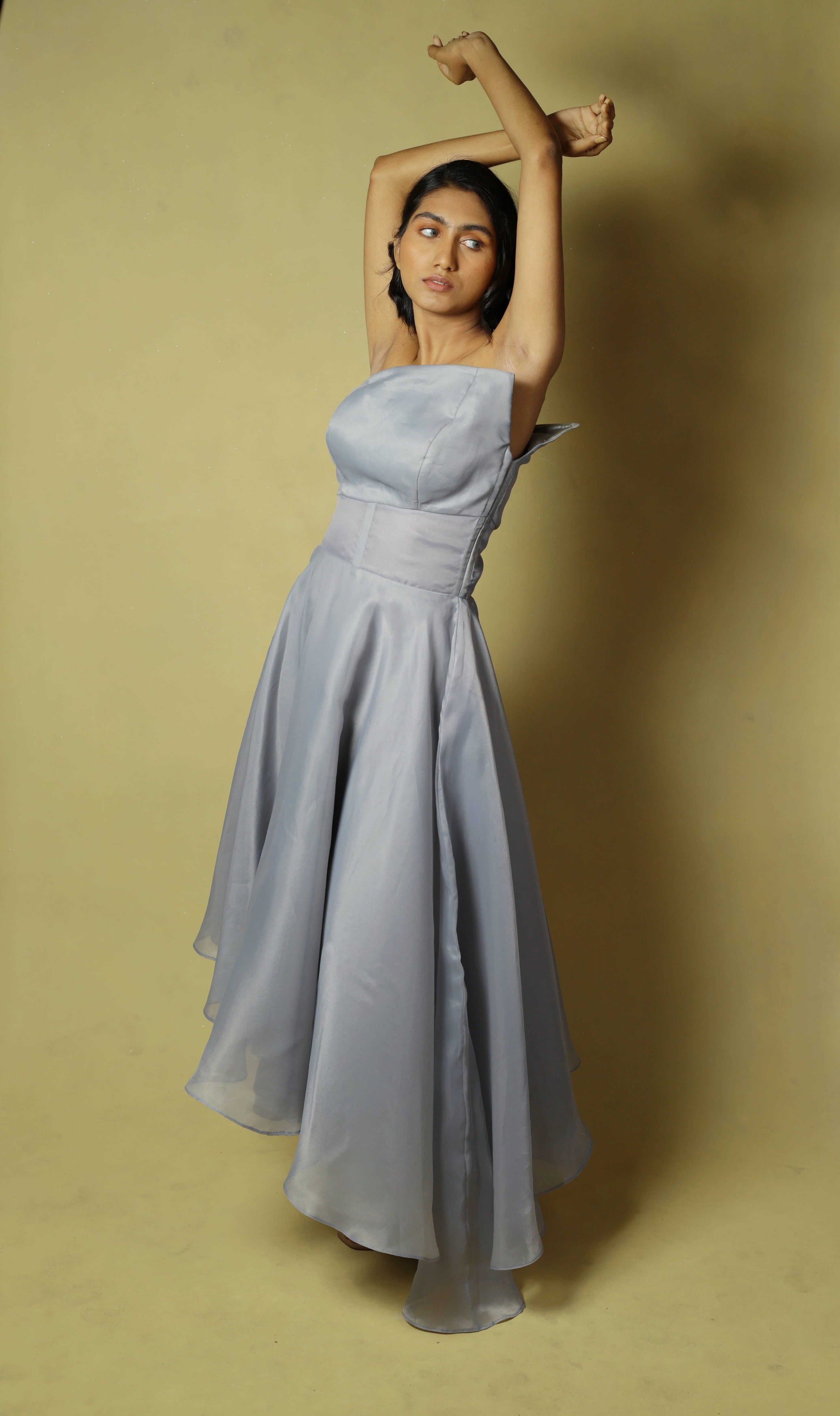 Model posing both hands above her head nonchalantly in a silver organza dress designed by Archana Karthick.