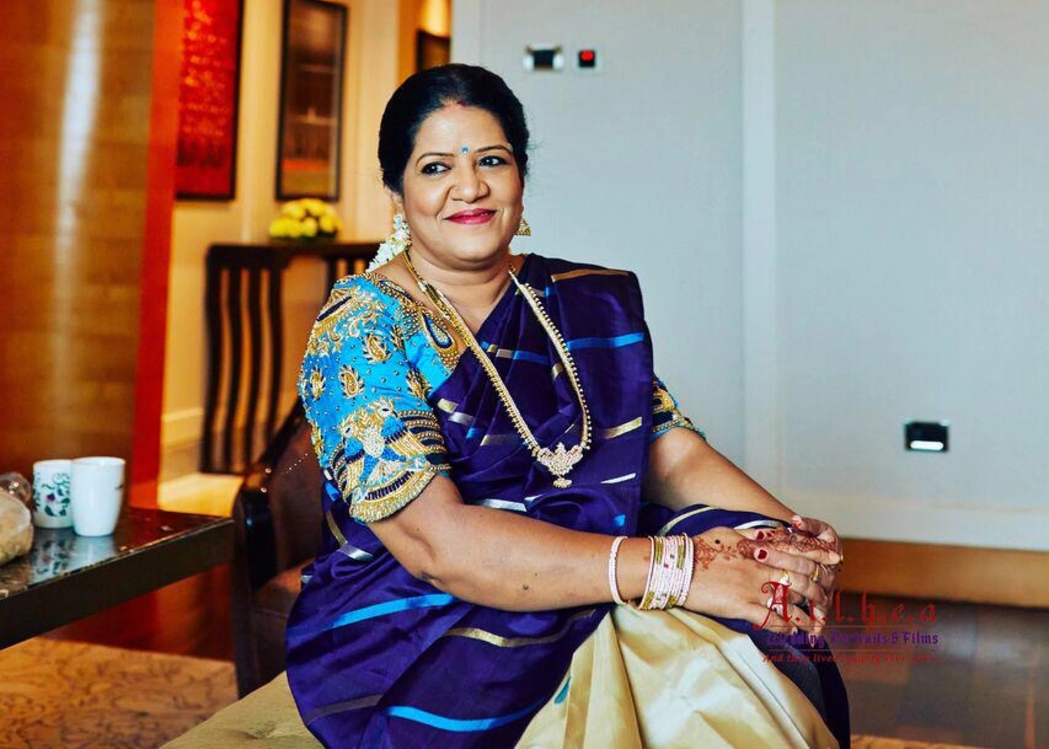 Mother of the bride posing for photo in a blue silk blouse, handcrafted with beads and resham by team Archana Karthick.