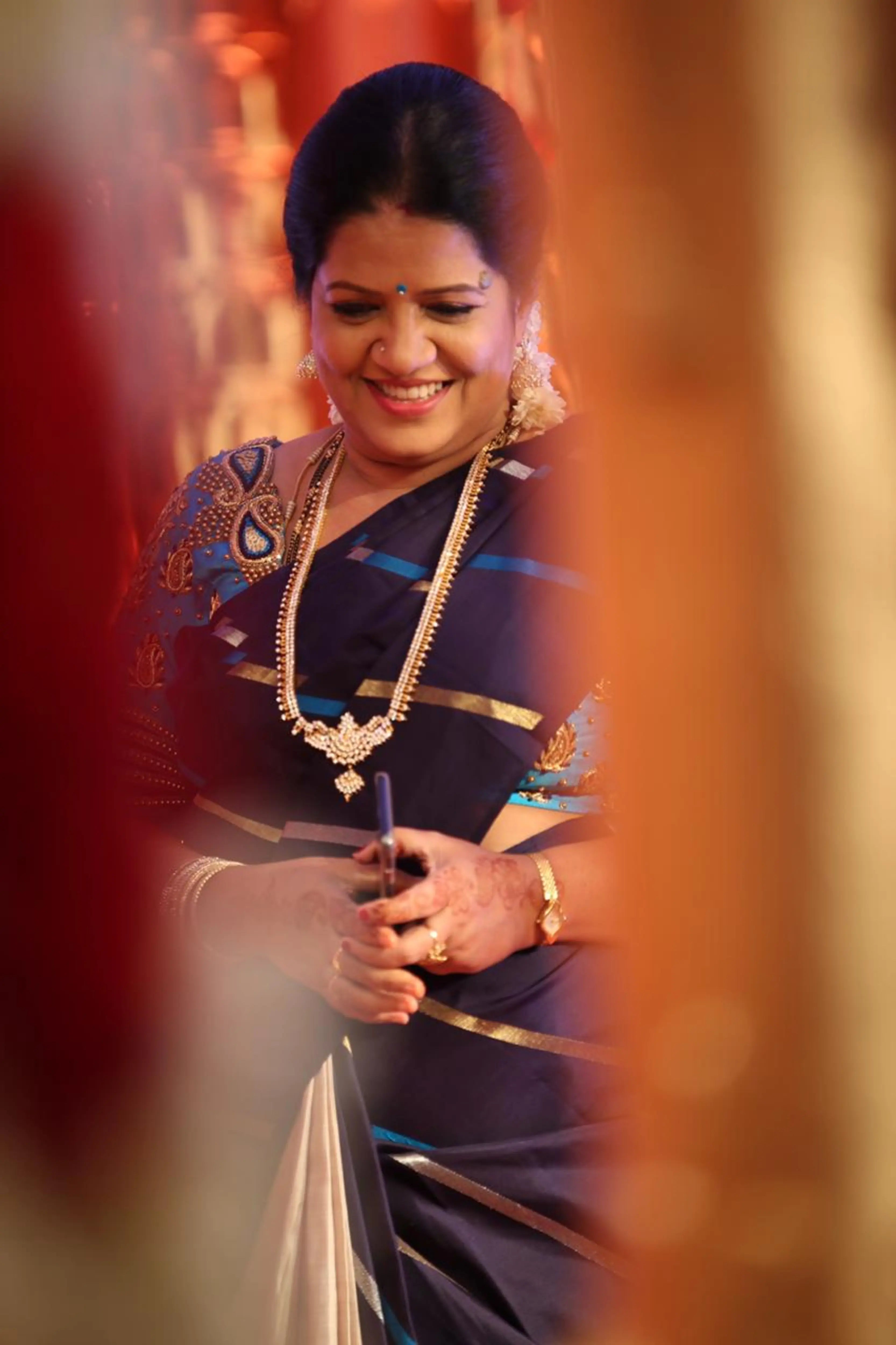 Mother of the bride smiling in a blue silk blouse, handcrafted with beads and resham by team Archana Karthick.