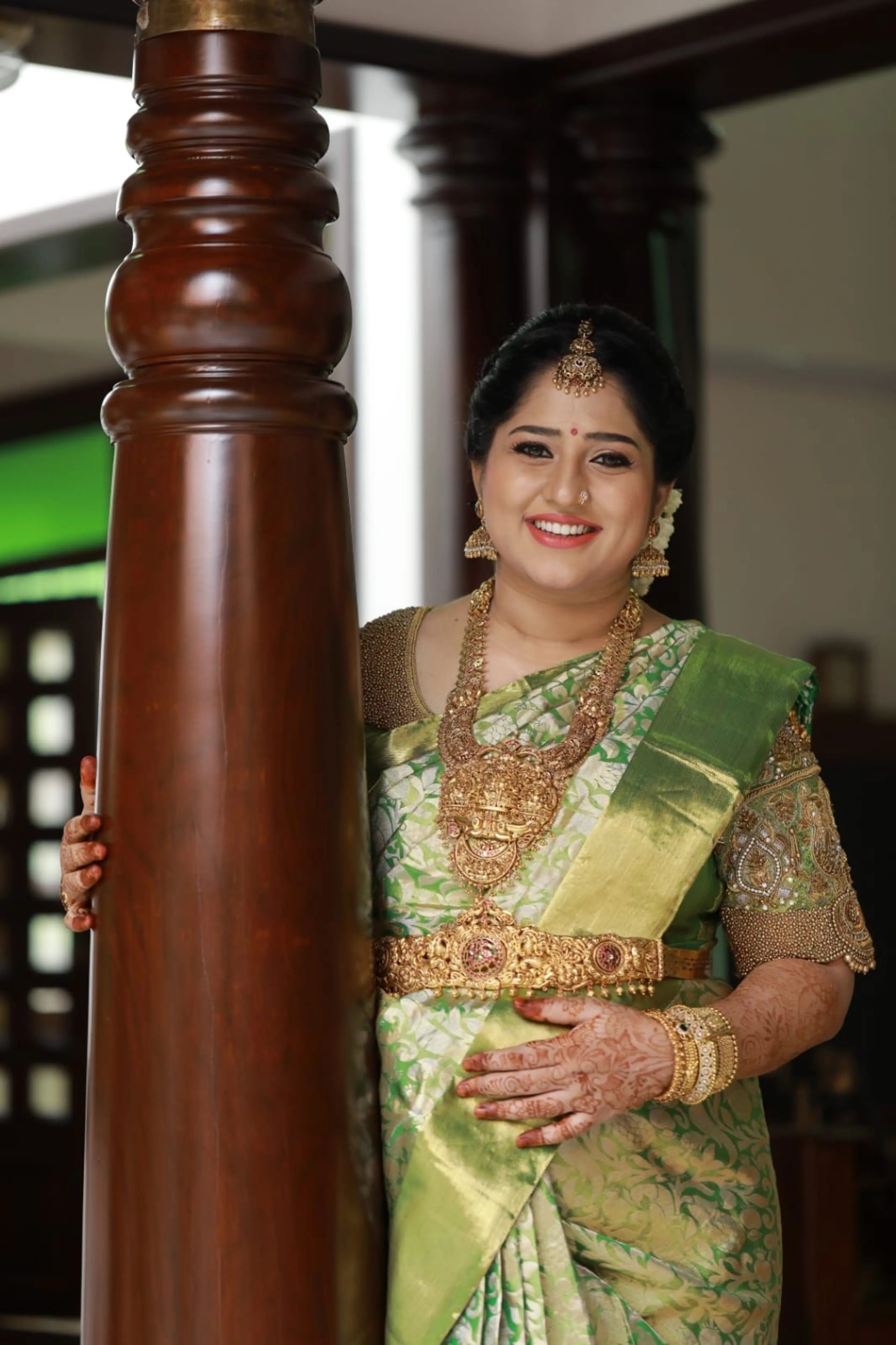 Mother to be, Dr Nivetha from Bangalore, smiling in a green silk blouse handcrafted by team Archana Karthick.