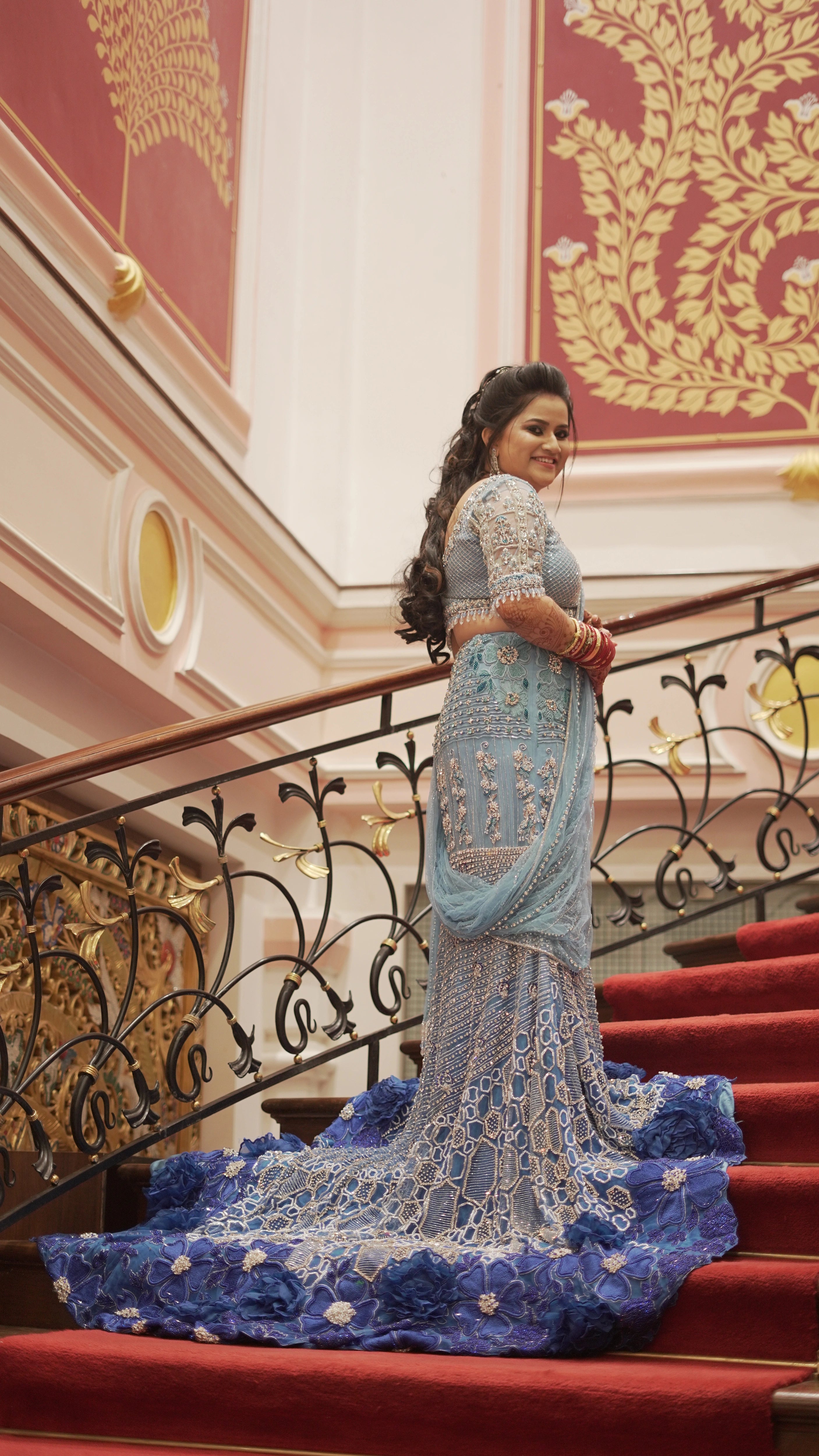 Pallabi from Odisha smiling for photo in a blue lehenga and sherwani handcrafted by team Archana Karthick