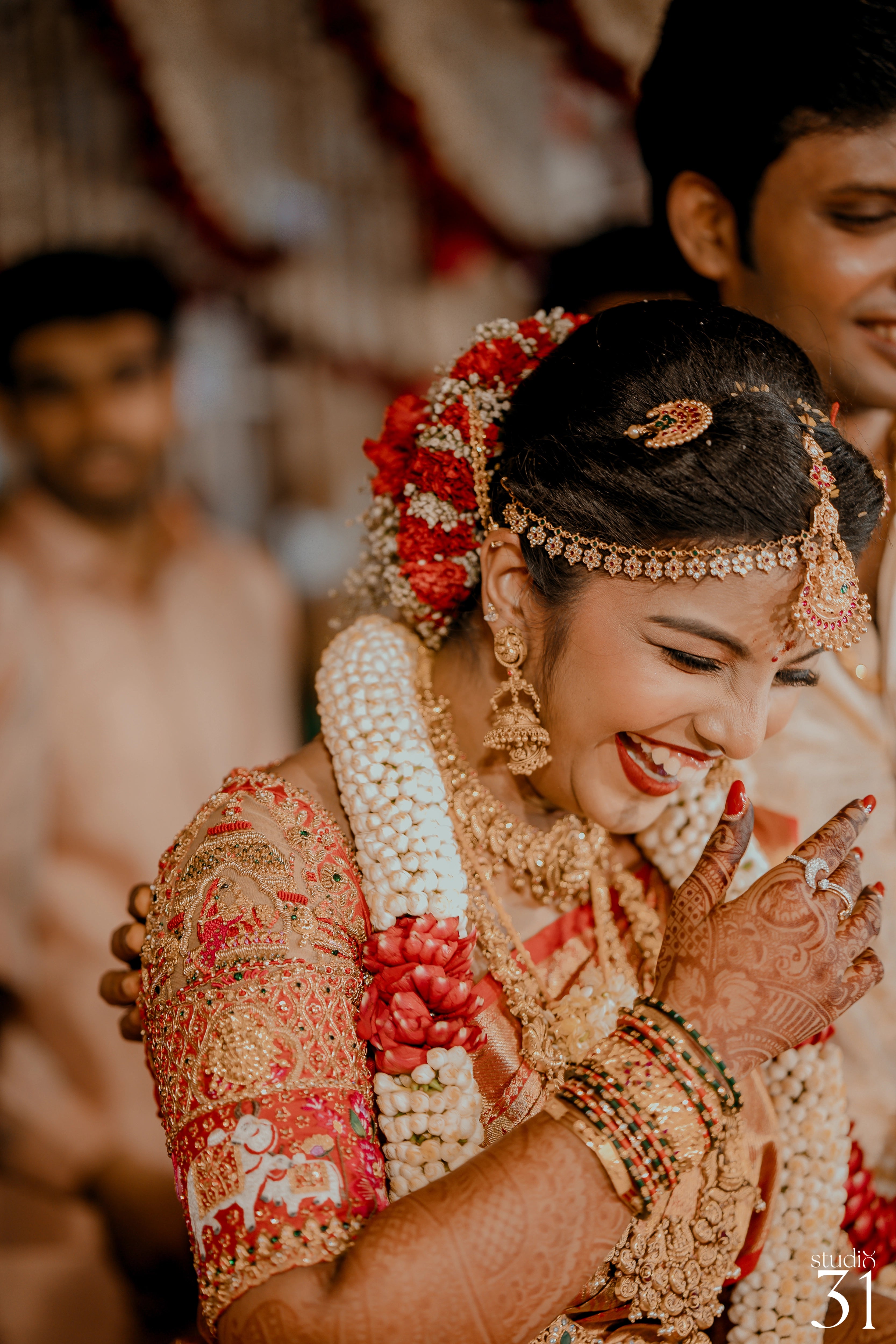 Pooja & Rhevanth smiiling during photoshoot for their wedding in red silk blouse and white silk veshti and shirt - intricately handcrafted by team Archana Karthick.