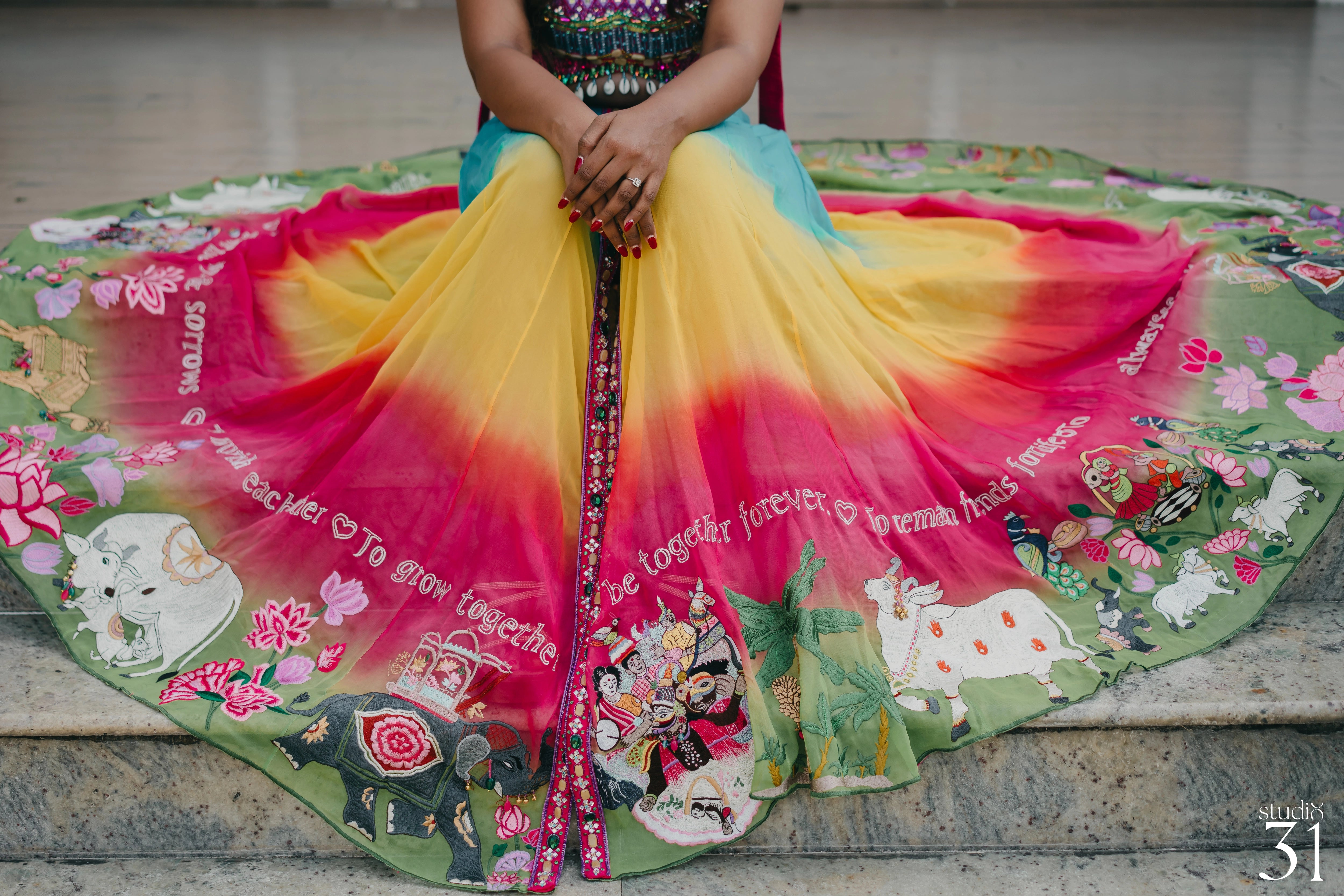 Pooja posing in a multi-colored fusion lehenga for her mehendi, dyed and intricately handcrafted by team Archana Karthick.