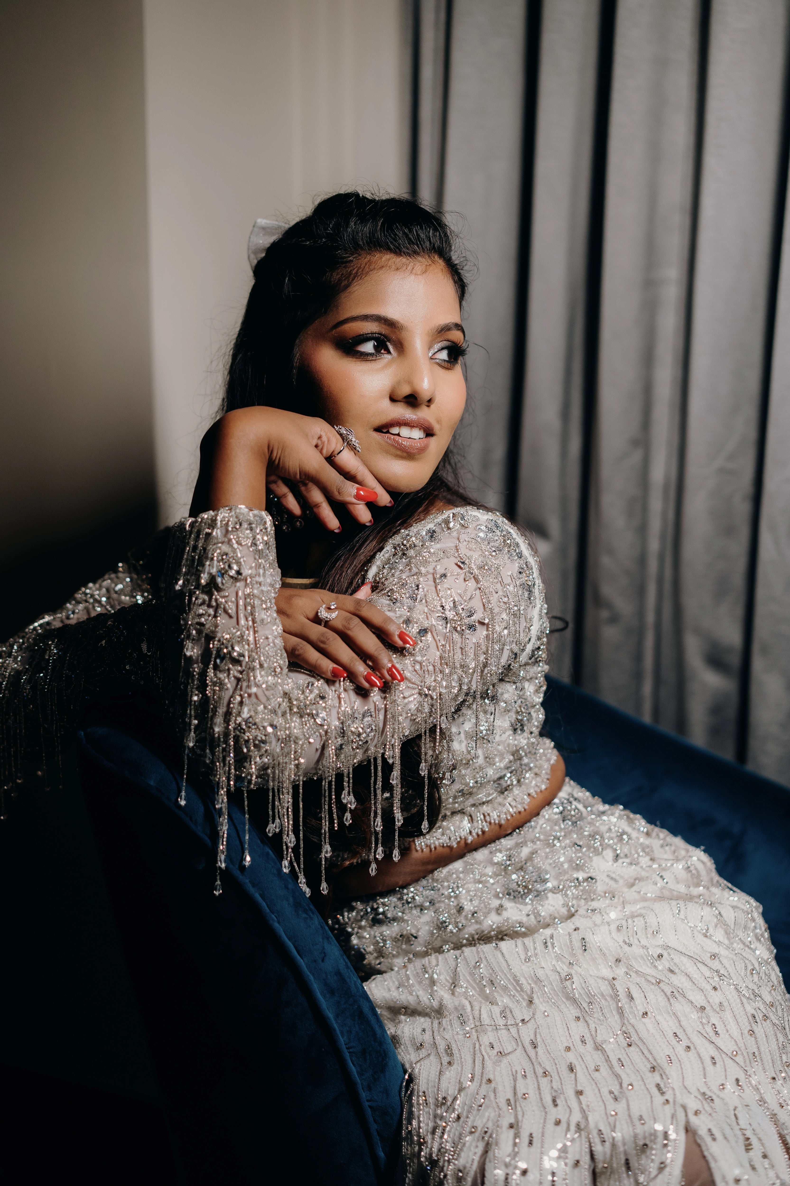 Pooja smiling for photo in a fusion lehenga for her sangeet intricately handcrafted by team Archana Karthick.