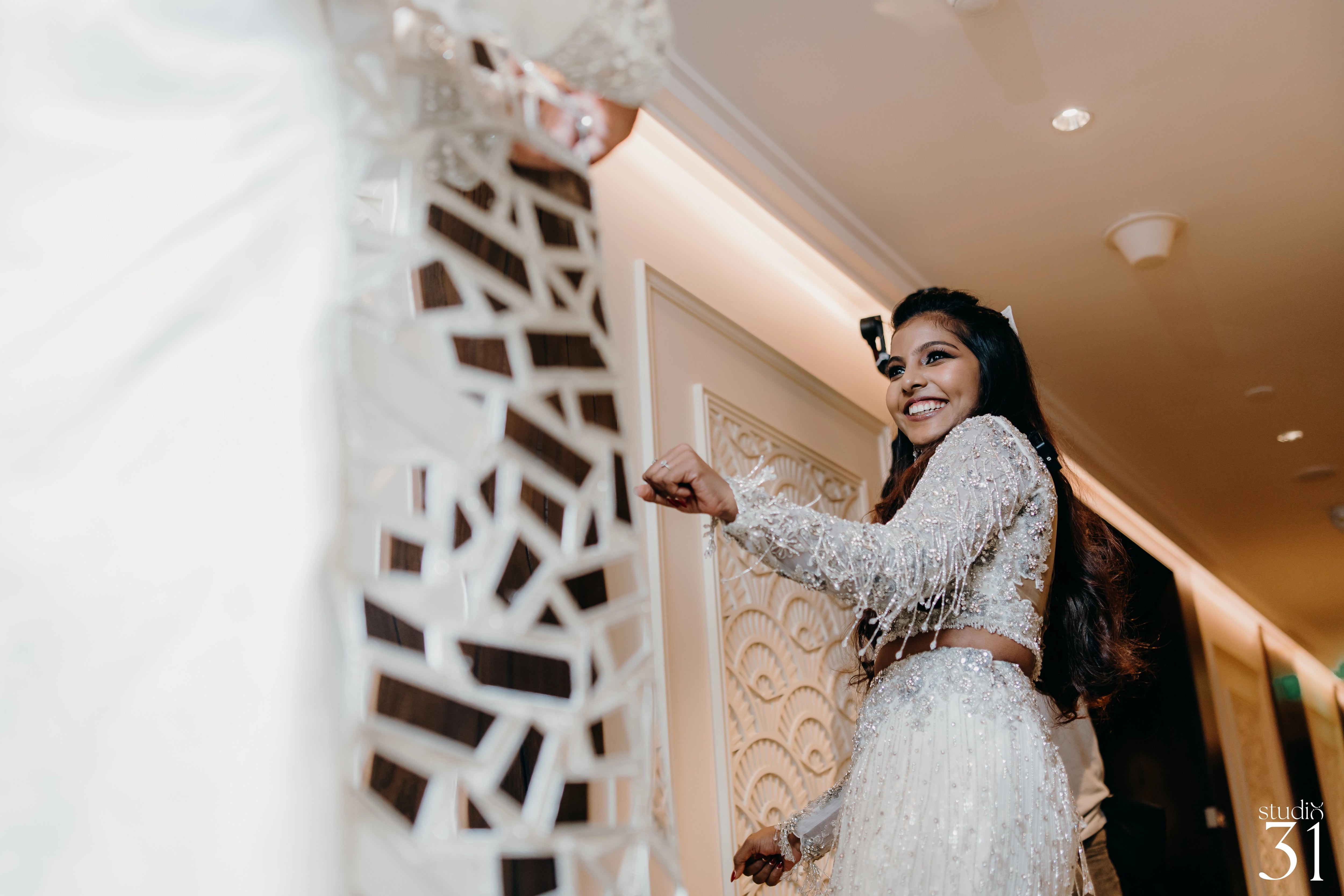 Pooja smiling with groom in a fusion lehenga for her sangeet intricately handcrafted by team Archana Karthick.