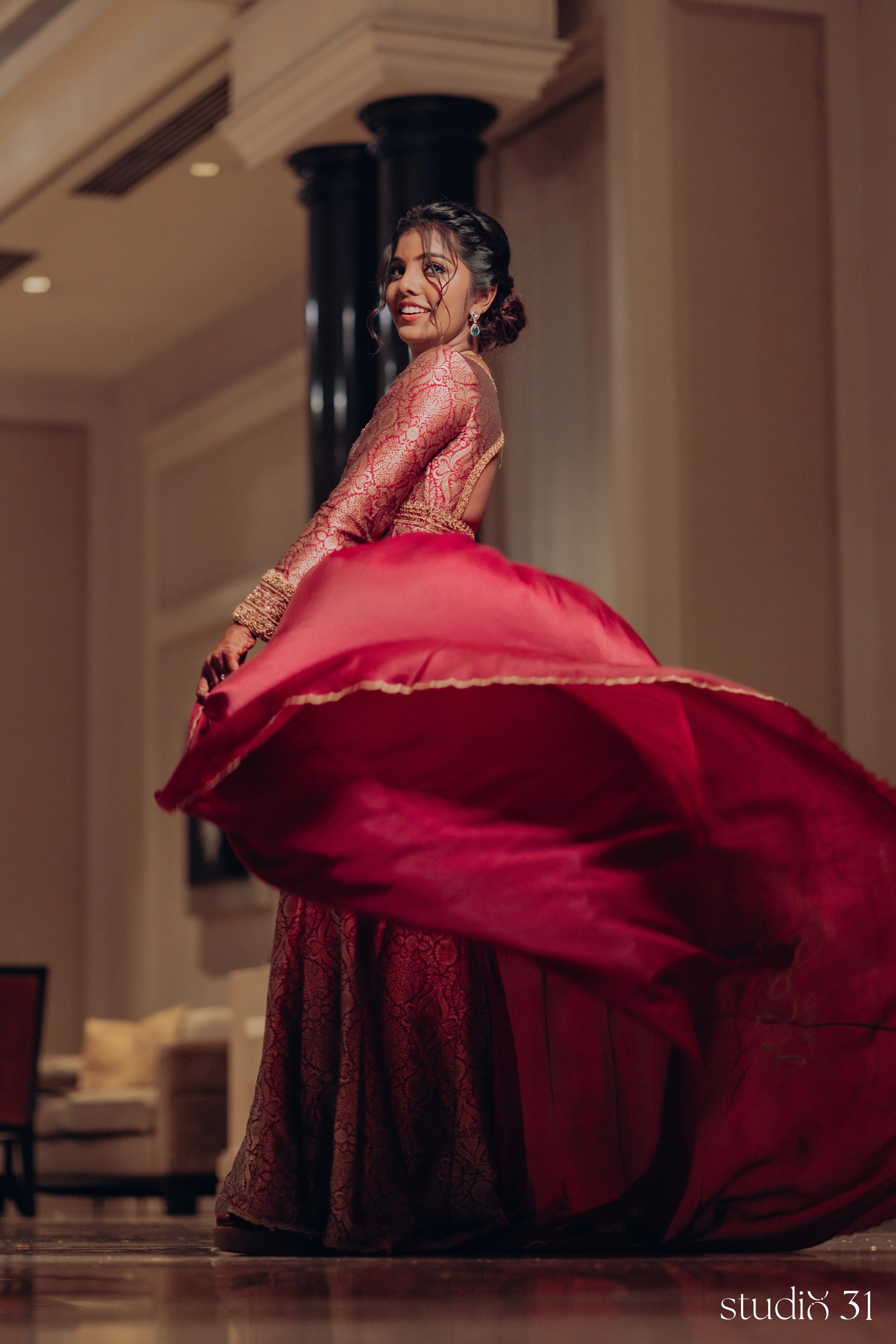 Pooja twirling during her engagement in a maroon ensemble by Archana Karthick