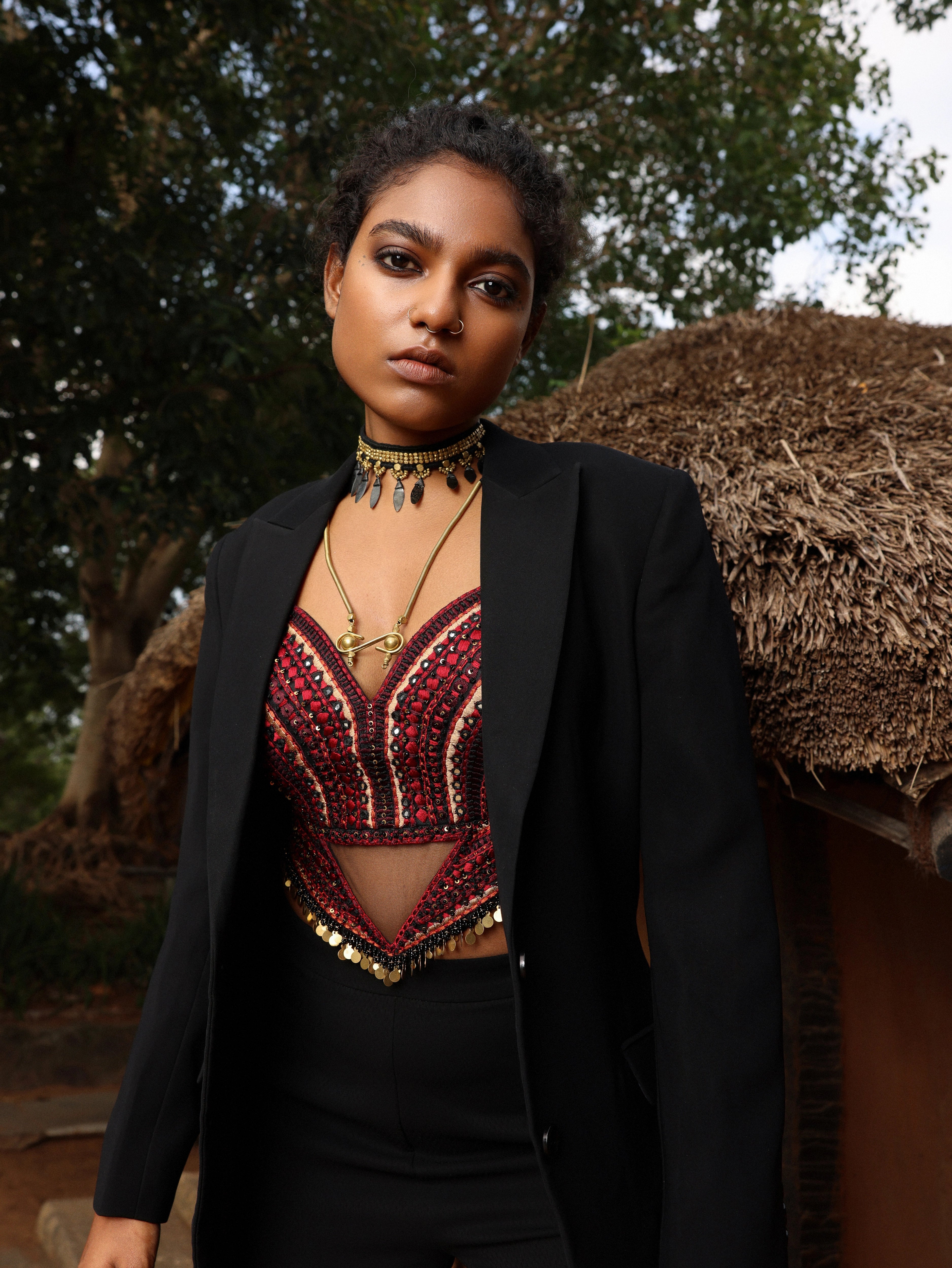 Posing in black pantsuit with handcrafted corset. Posing outside a hut.