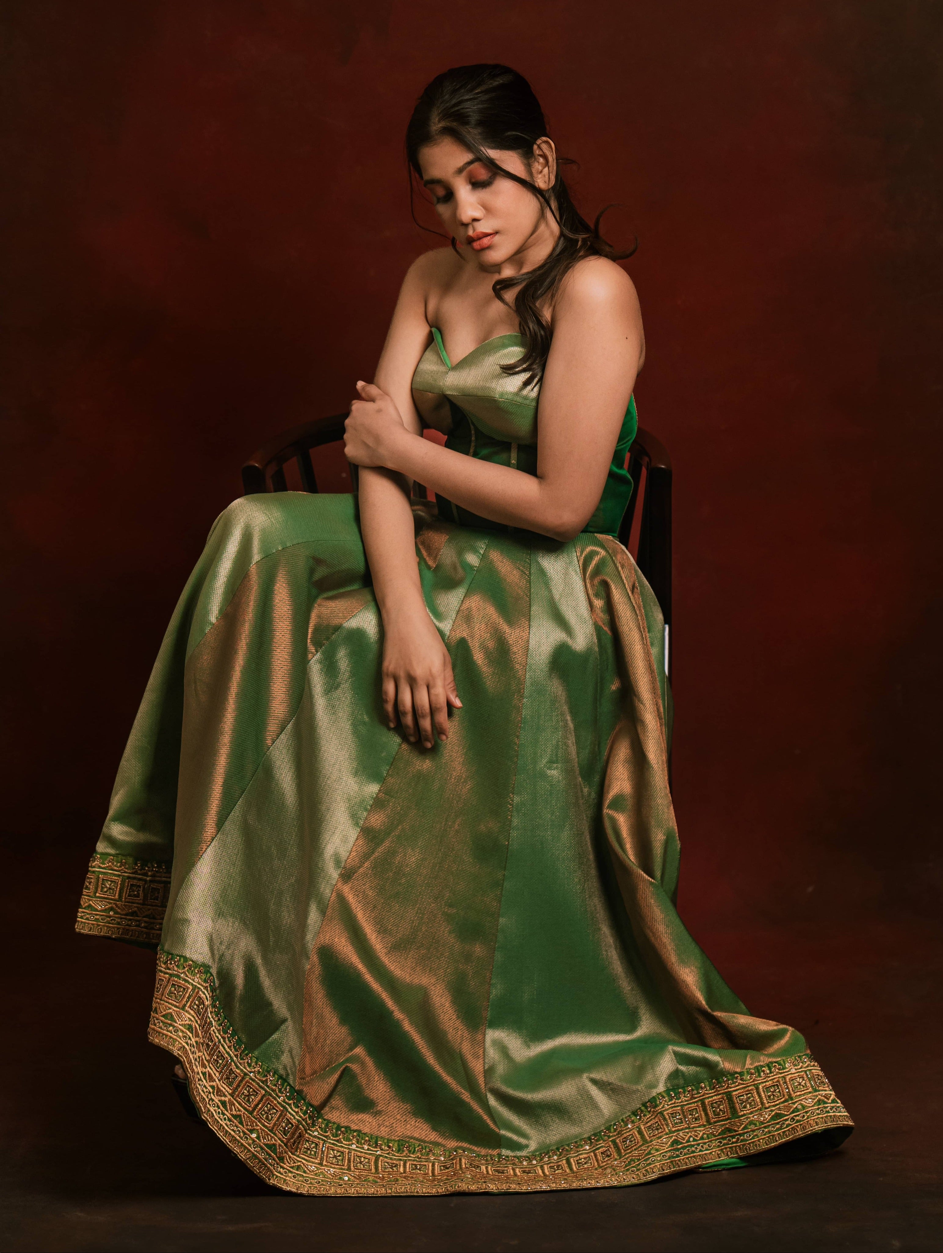 Posing seated in a silk corset designer dress intricately handcrafted with zari, gold beads, and antique cutdana by team Archana Karthick.