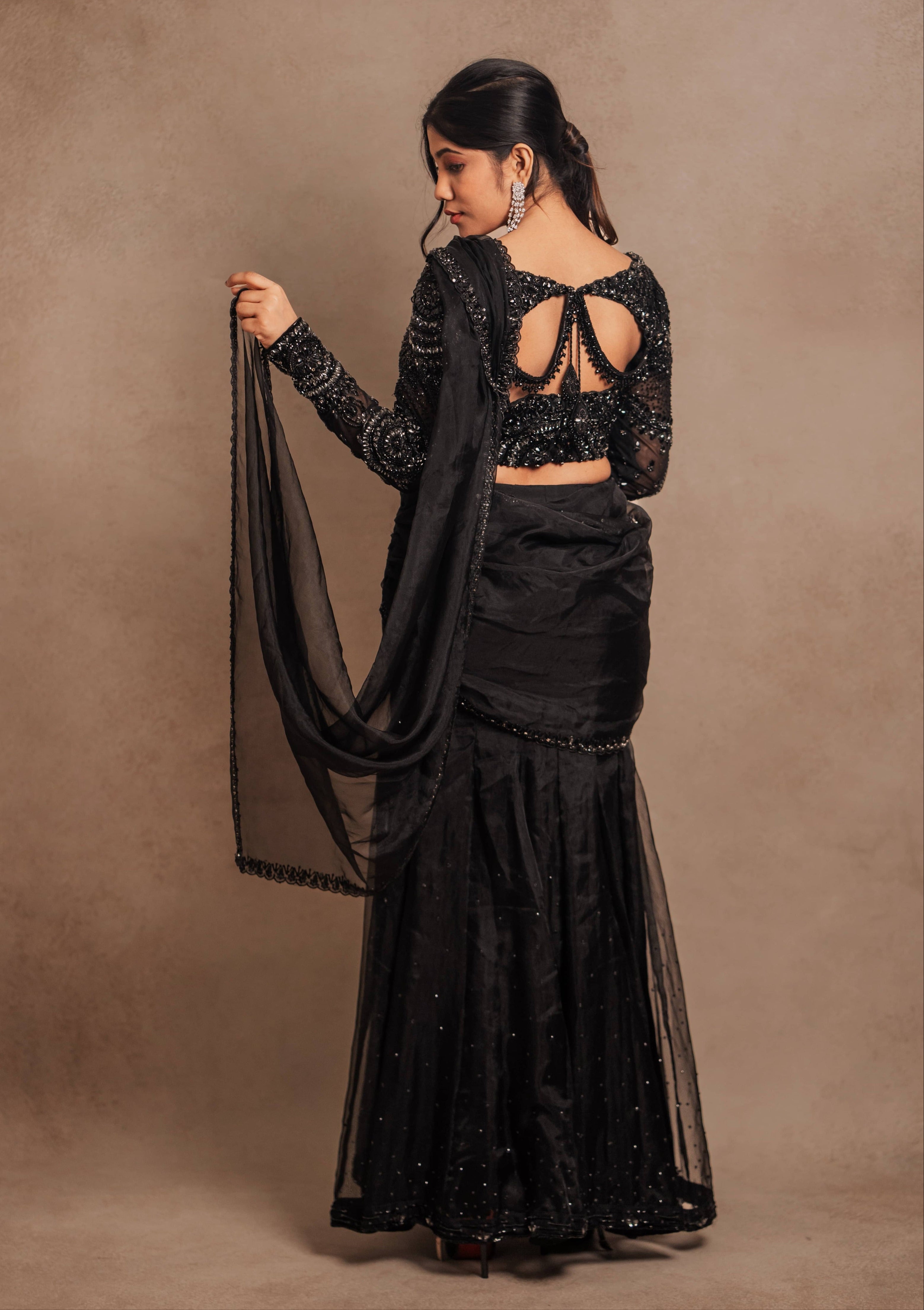 Showcasing back design details in a black organza mermaid saree intricately handcrafted with stones, crystals, and sequins designed by team Archana Karthick.