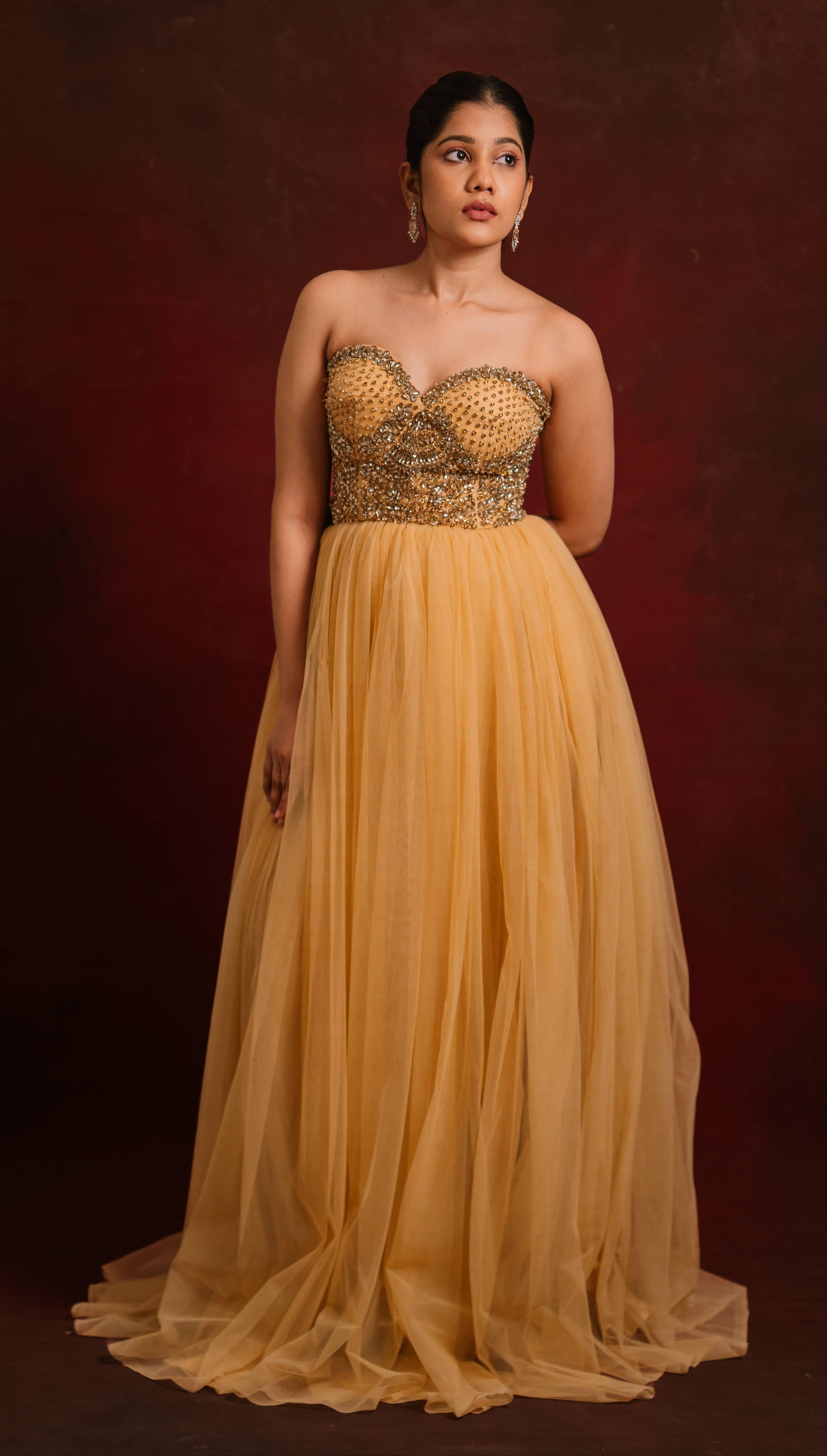 Showcasing full front profile in a gold corset dress intricately handcrafted with stones and sequins designed by team Archana Karthick.