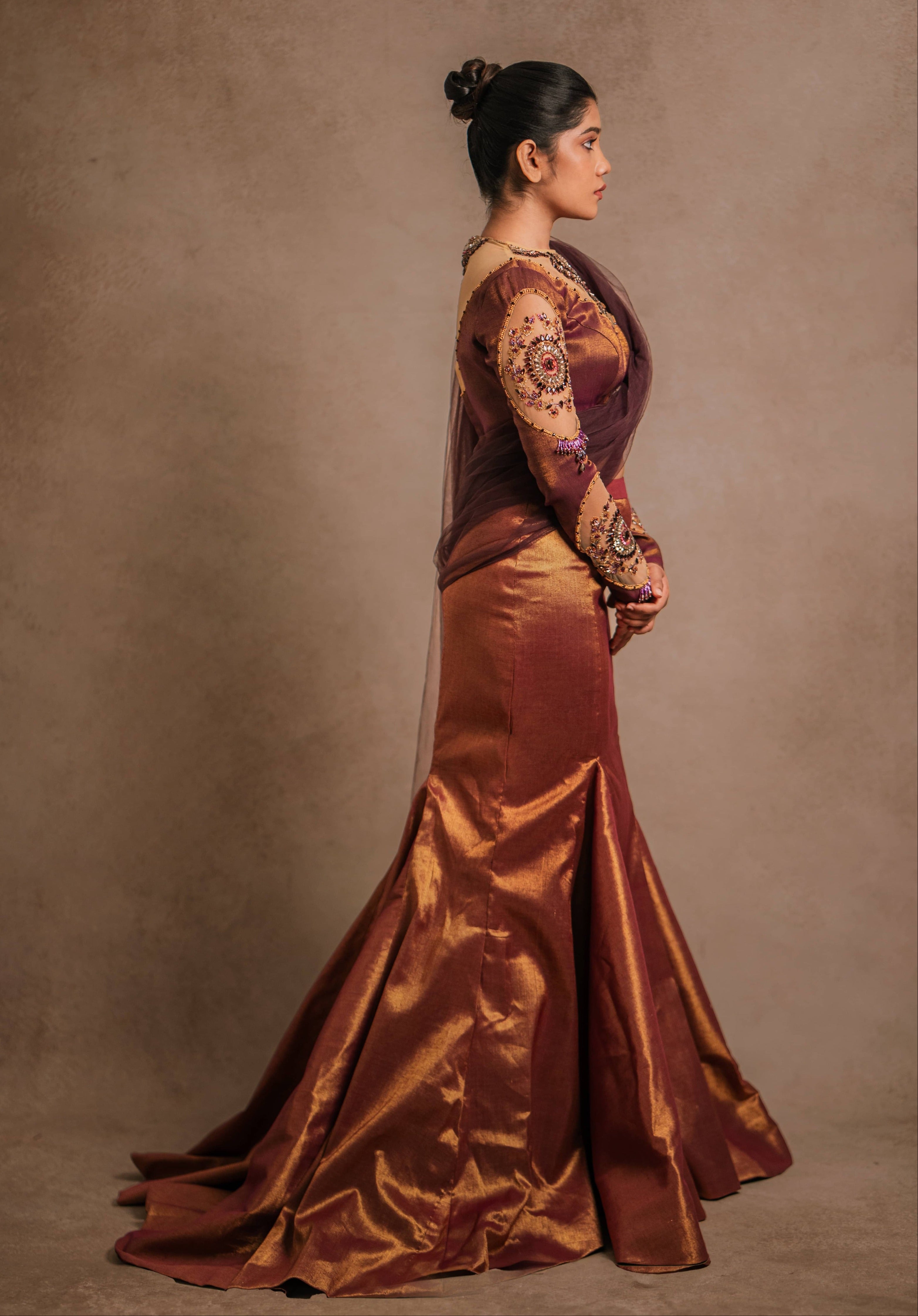 Showcasing full side profile of a tissue lehenga with a mermaid skirt & a tulle dupatta intricately handcrafted with stones, crystals, and sequins by team Archana Karthick.