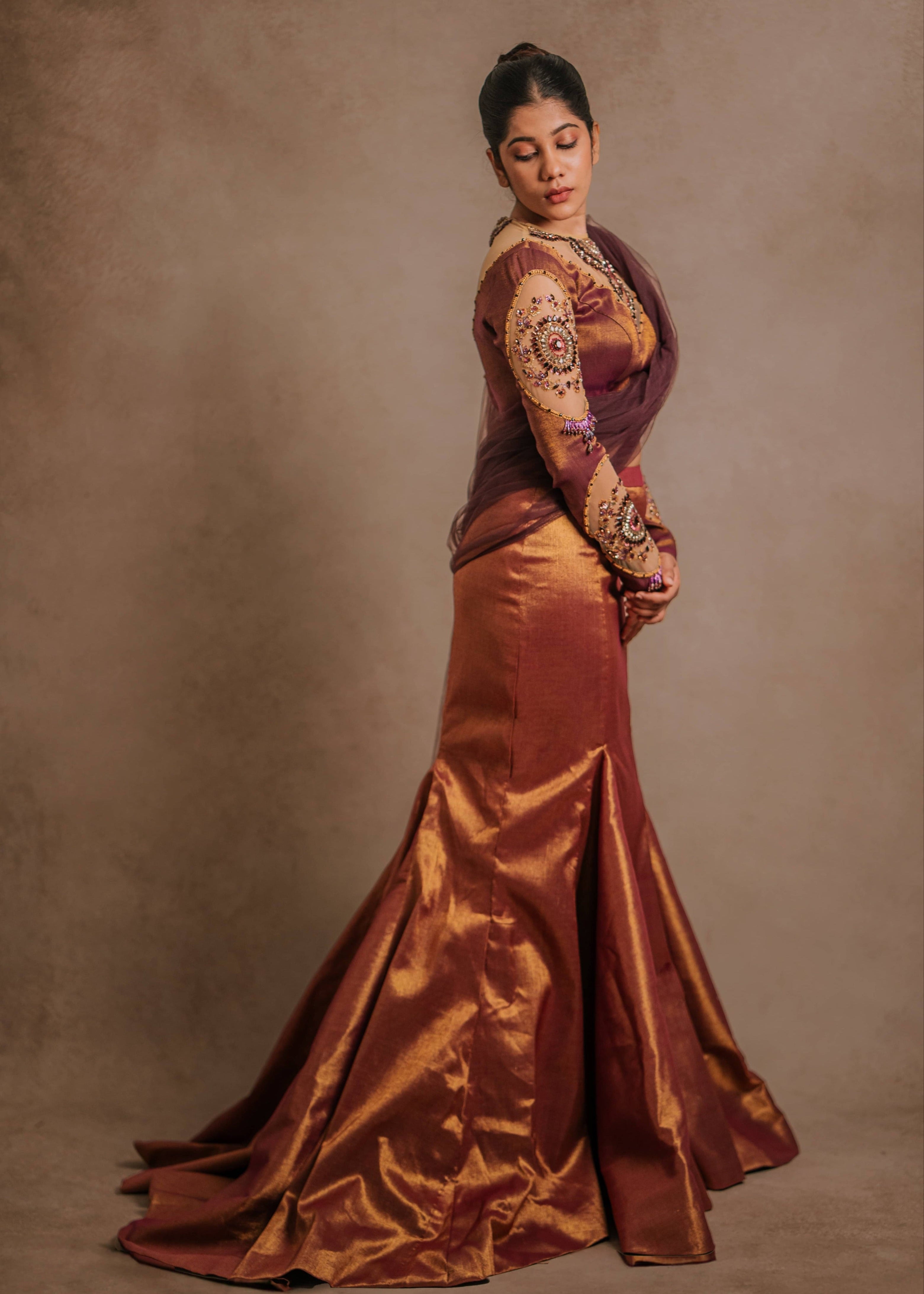 Showcasing side profile in a tissue lehenga with a mermaid skirt & a tulle dupatta intricately handcrafted with stones, crystals, and sequins by team Archana Karthick.