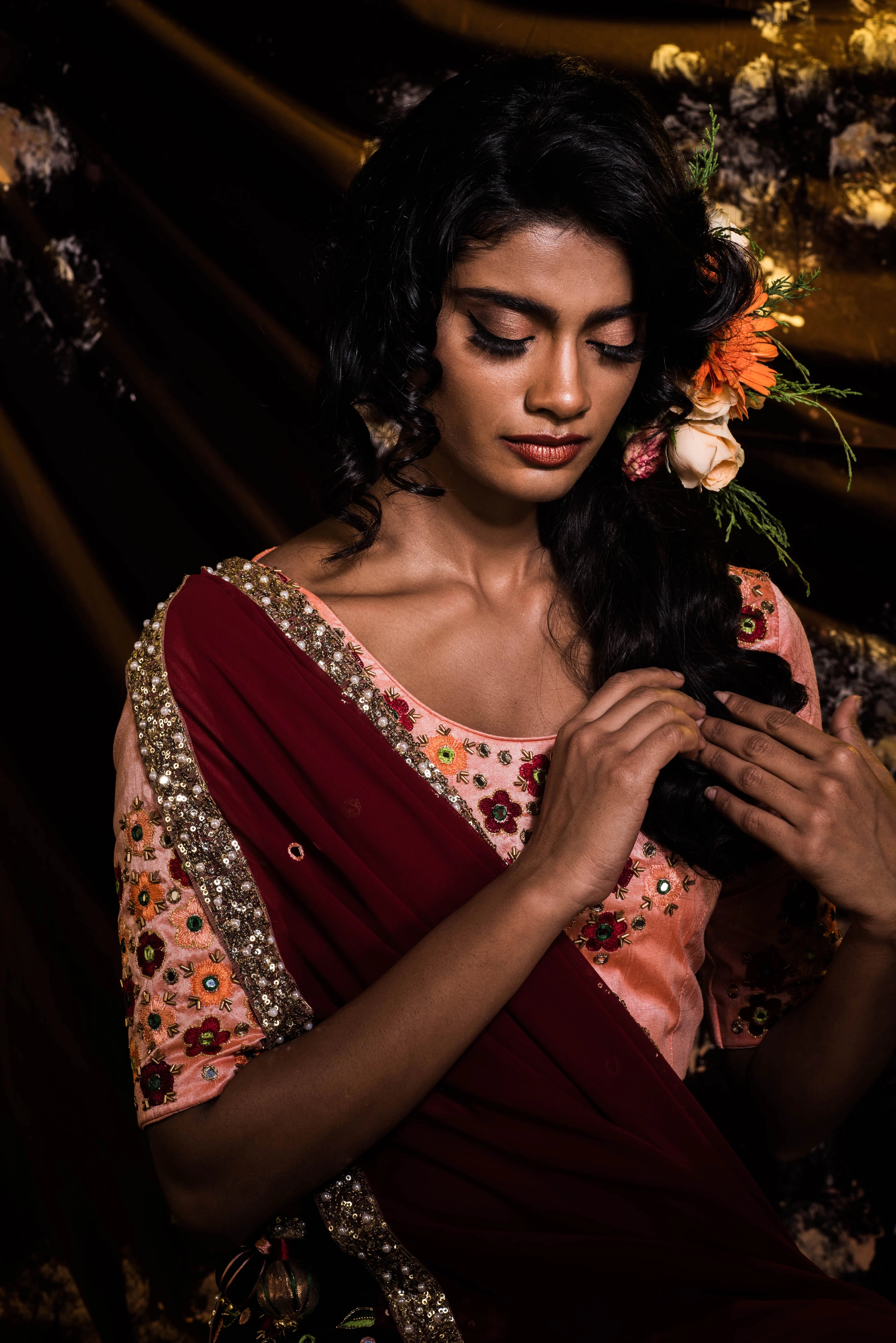 Supermodel Archana Akil Kumar looking down in a rawsilk peach and bottle green lehenga with a maroon georgette dupatta intricately handcrafted by team Archana Karthick.