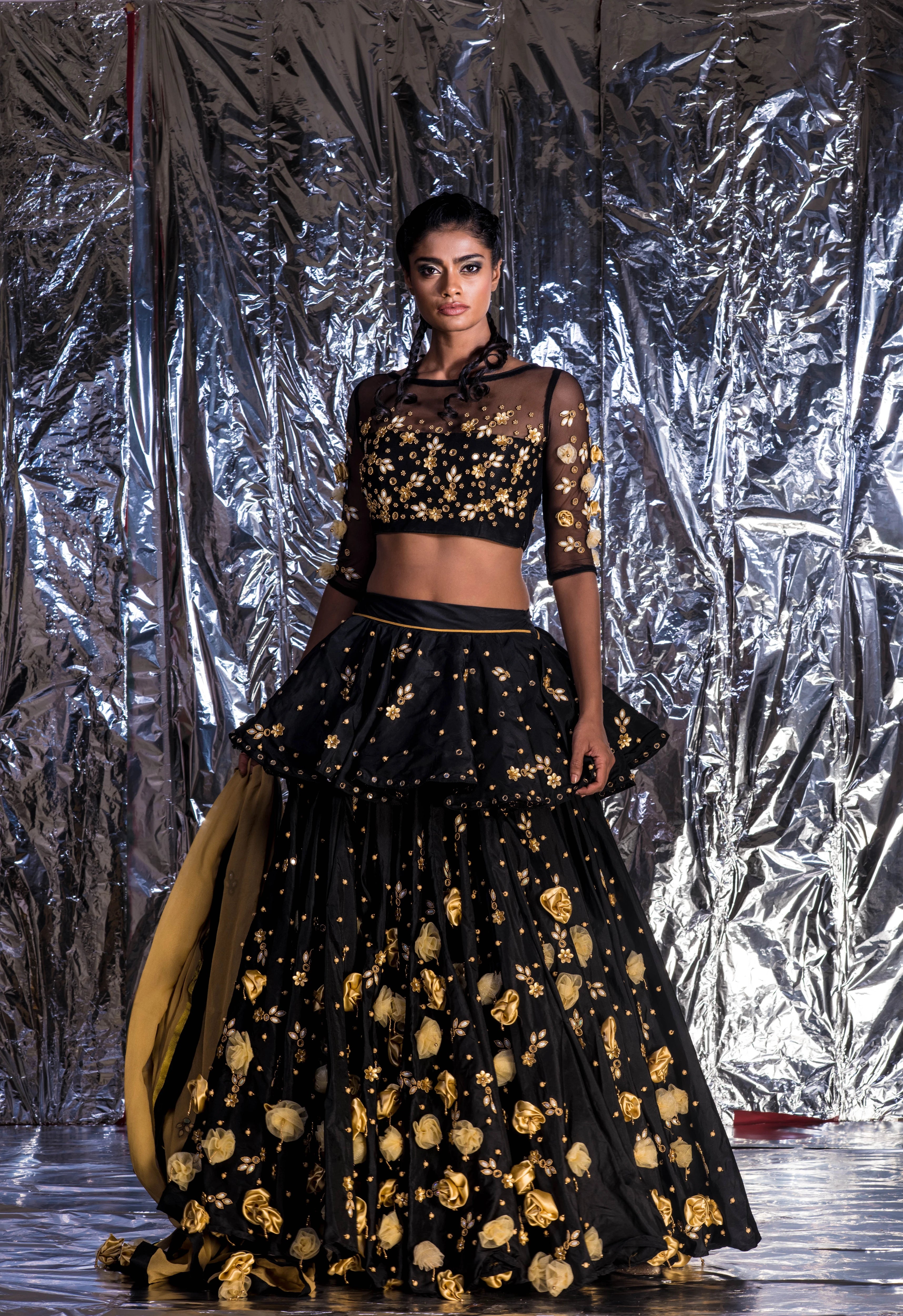Supermodel Archana Akil Kumar posing straight at camera in a black taffeta lehenga with a gold georgette dupatta intricately handcrafted with appliques, pearls, mirror and beads.
