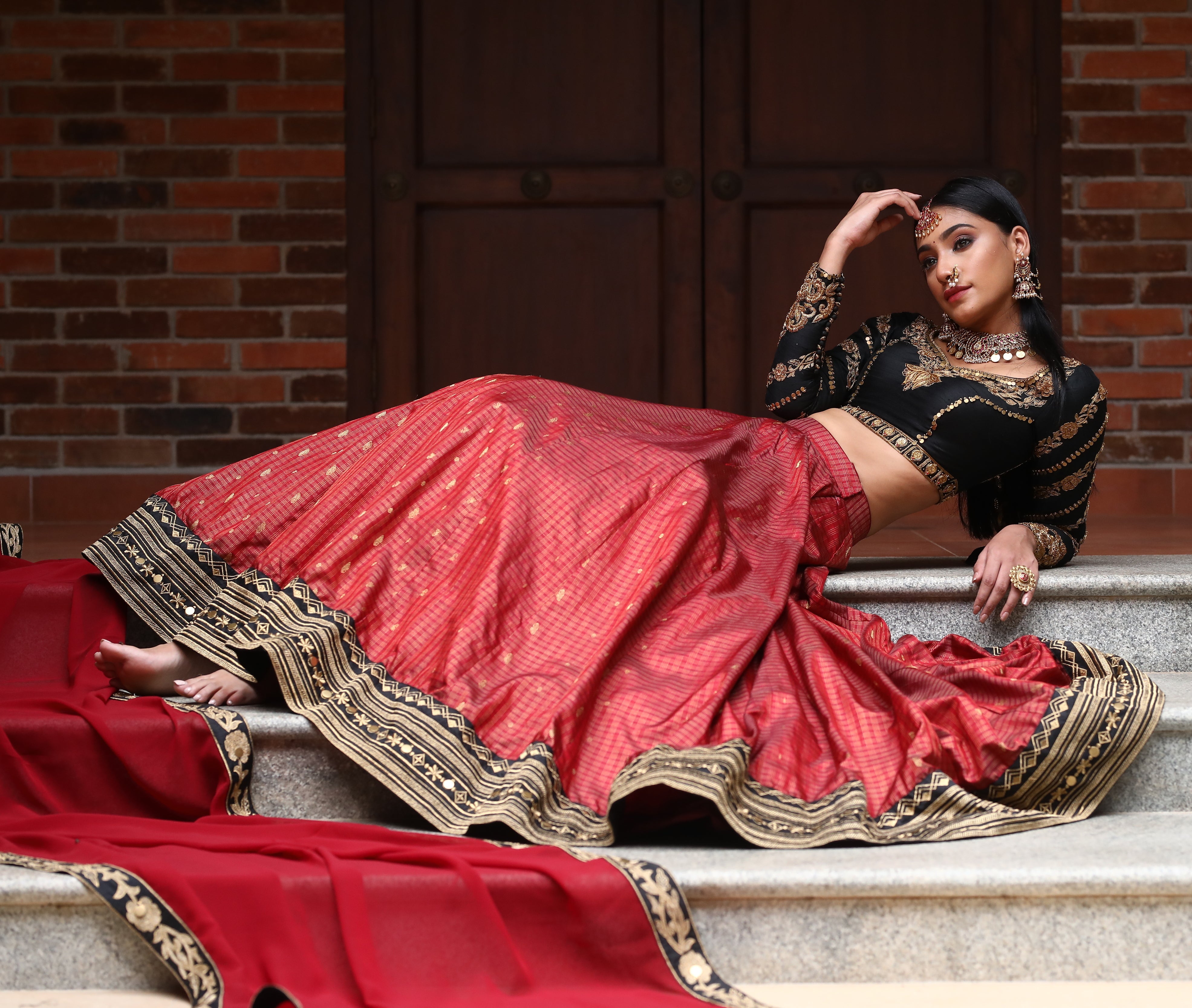miss india 2018 and actress Anukreethy Vas in lehenga designed by archana karthick posing sitting sideways on stairs with hand on head