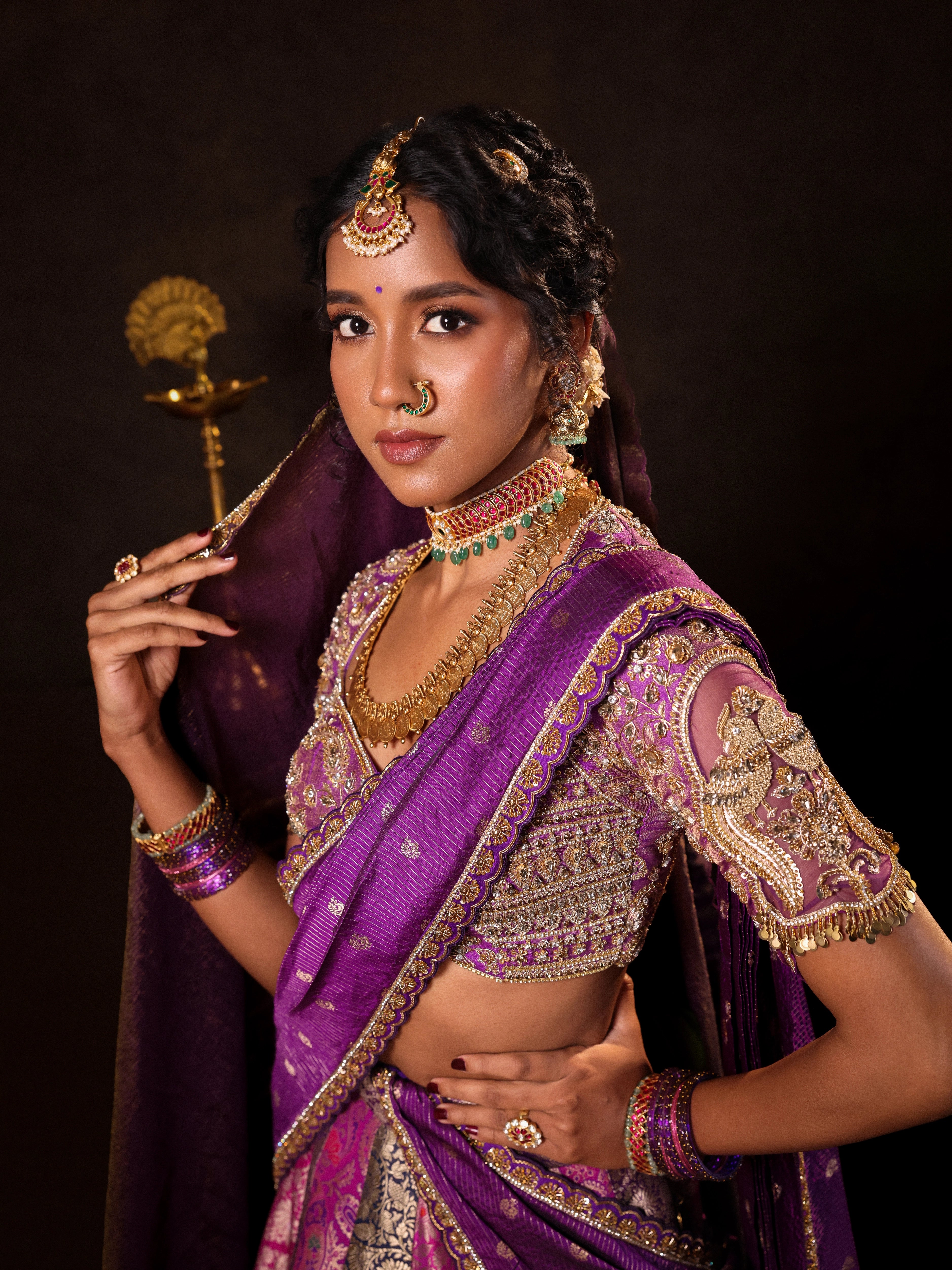 Model Gayathri Dhanasekar poses in a purple banarasi brocade silk half saree with glass bangles and NAC jewellery.